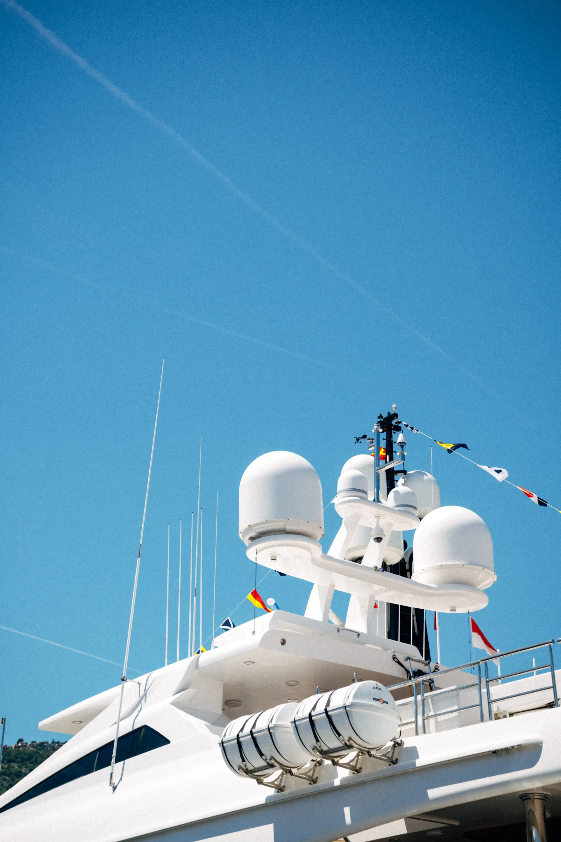 Yacht radar and communication equipment silhouetted against a clear blue Mediterranean sky.