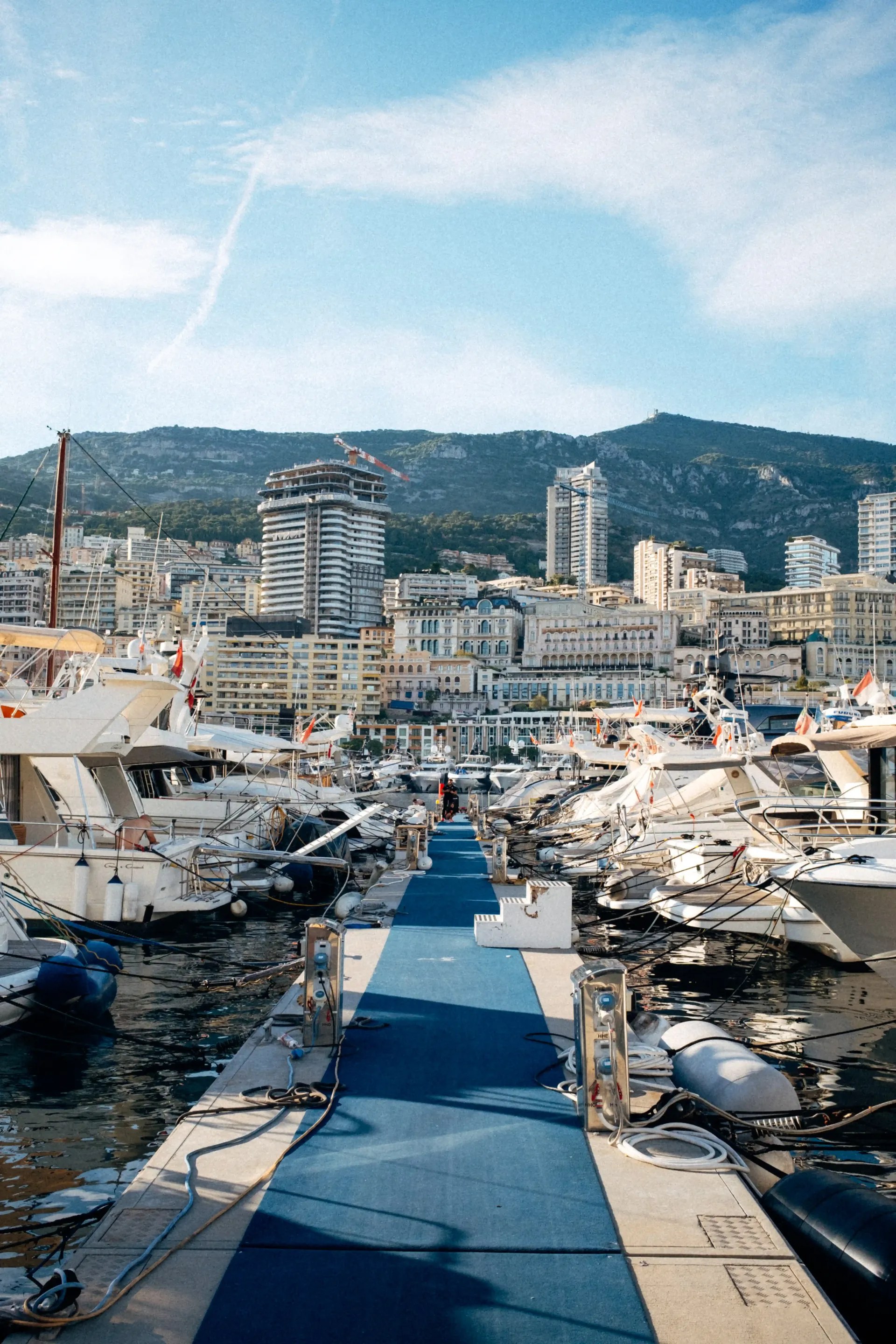 Elevated view over Monaco marina with rows of luxury yachts and waterfront development.