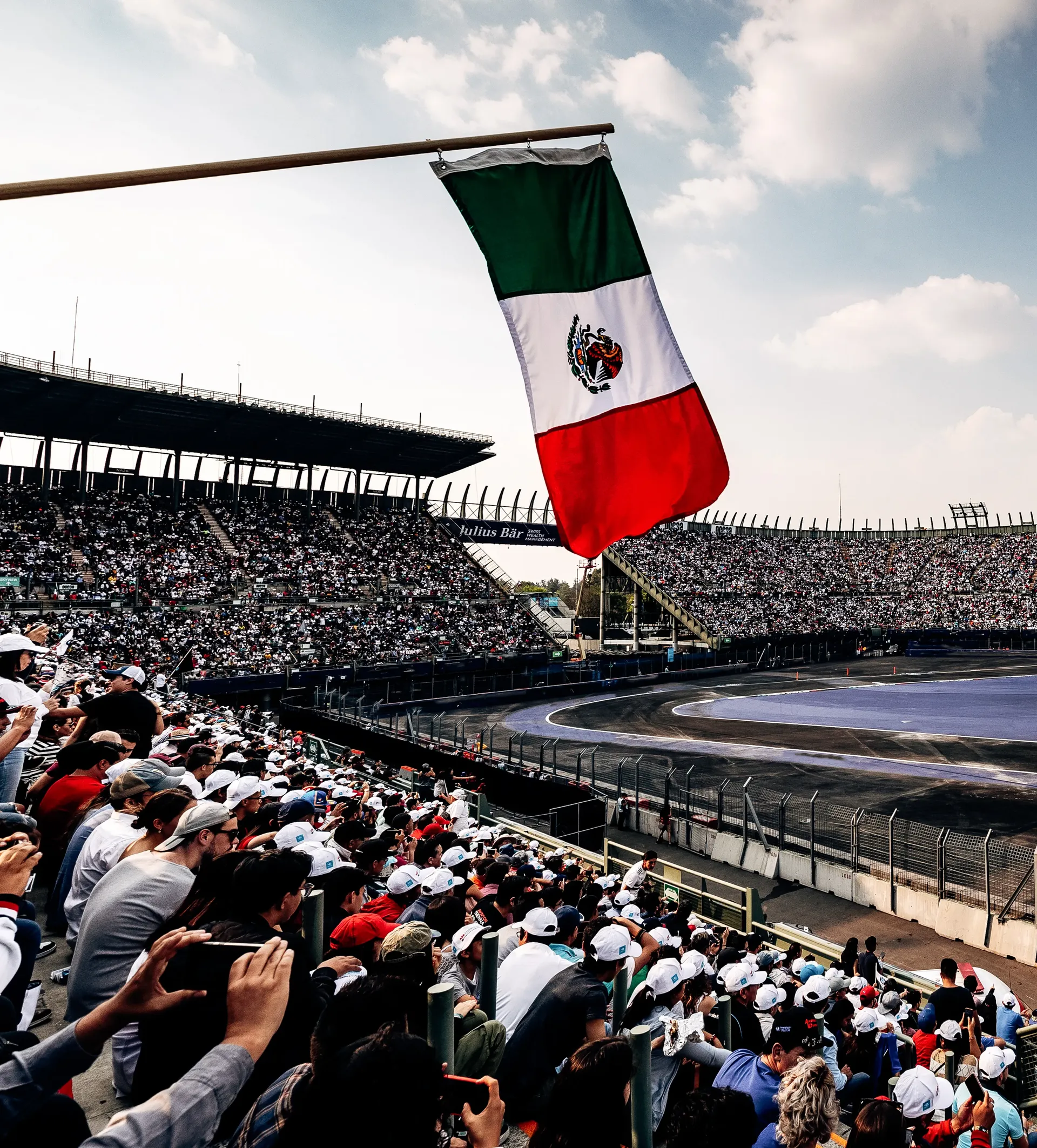 Mexican flag flying above packed grandstands in the Foro Sol stadium section at Autodromo Hermanos Rodriguez
