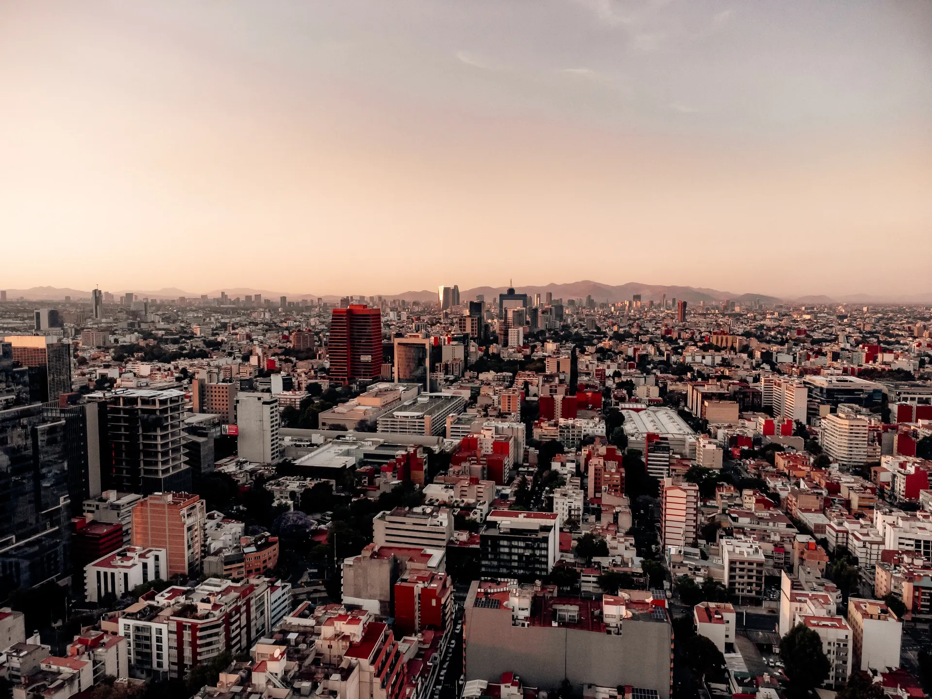 Aerial view of the Mexico City skyline at dusk with mountains in the distance