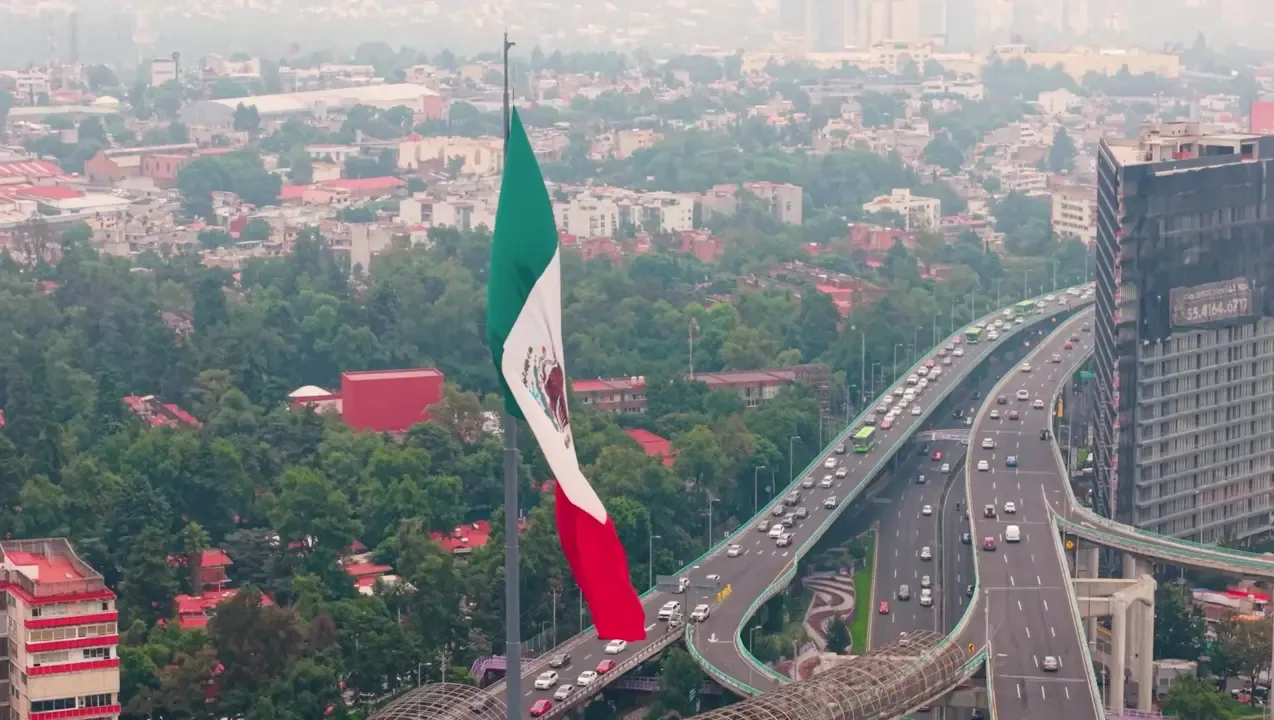 Aerial view of the Mexico City skyline at dusk with mountains in the distance