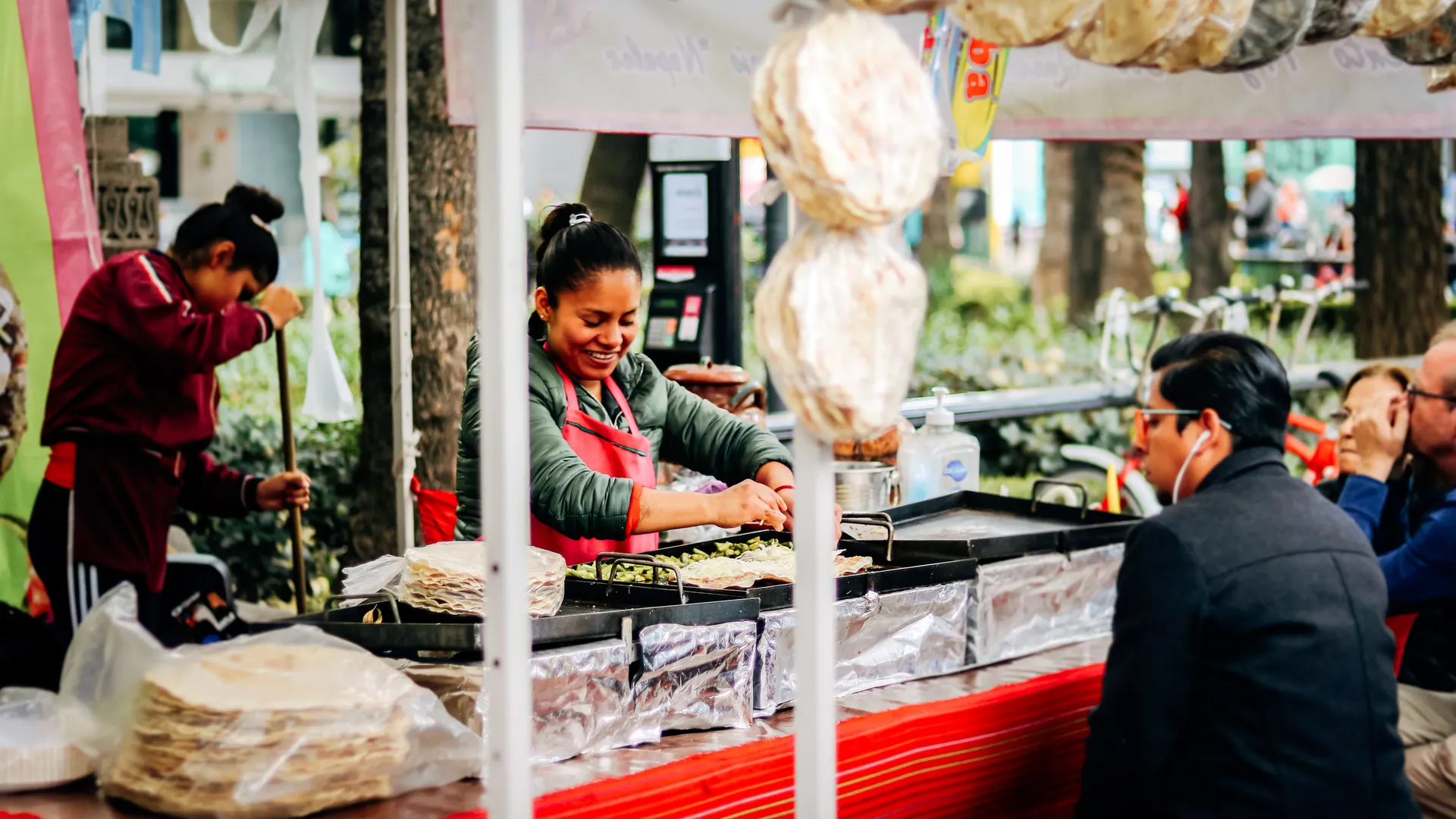 Street food vendor preparing tortillas with nopales on a griddle at a stall in Mexico City