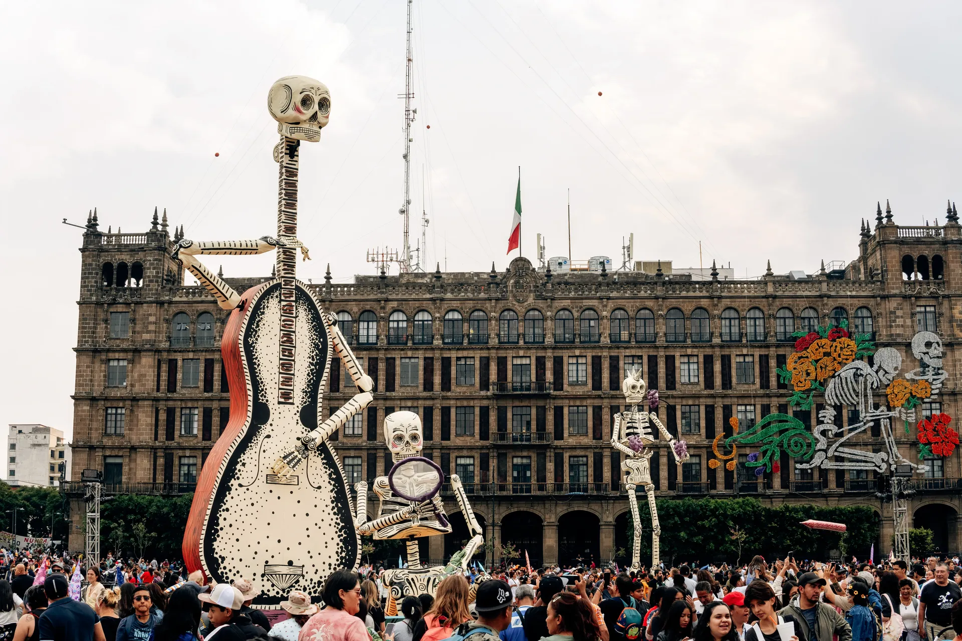 Giant skeleton sculptures with a guitar in front of a historic building in Mexico City for Día de los Muertos