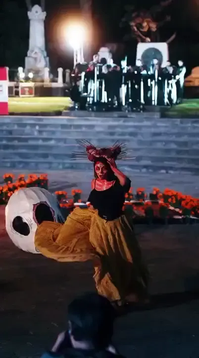Dancer in skeleton make-up and a flowing yellow skirt spinning at a Día de los Muertos celebration in Mexico City