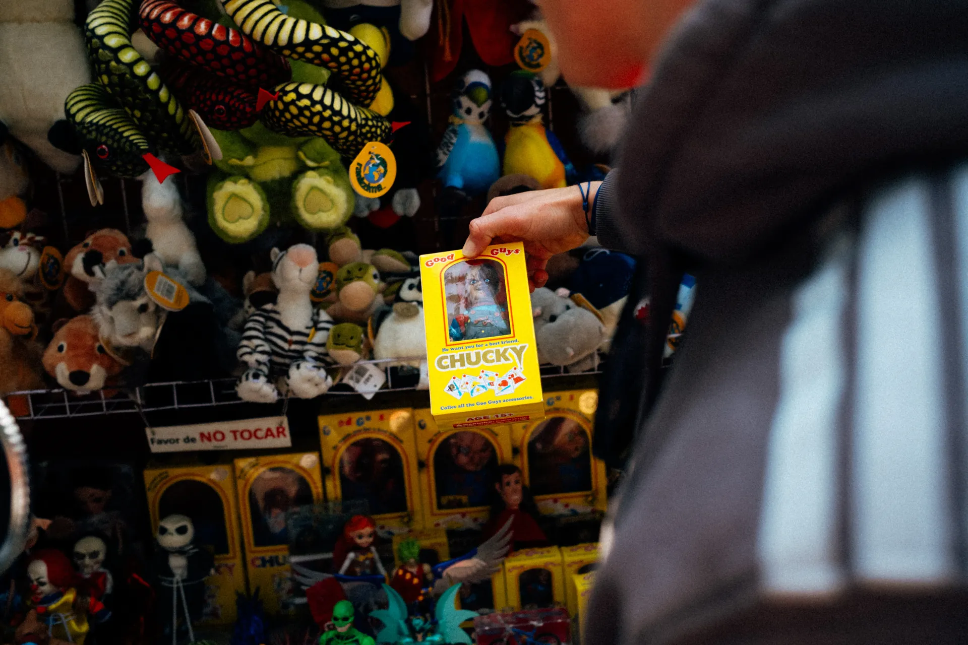 Hand holding a boxed doll at a toy stall full of plush animals in Mexico City