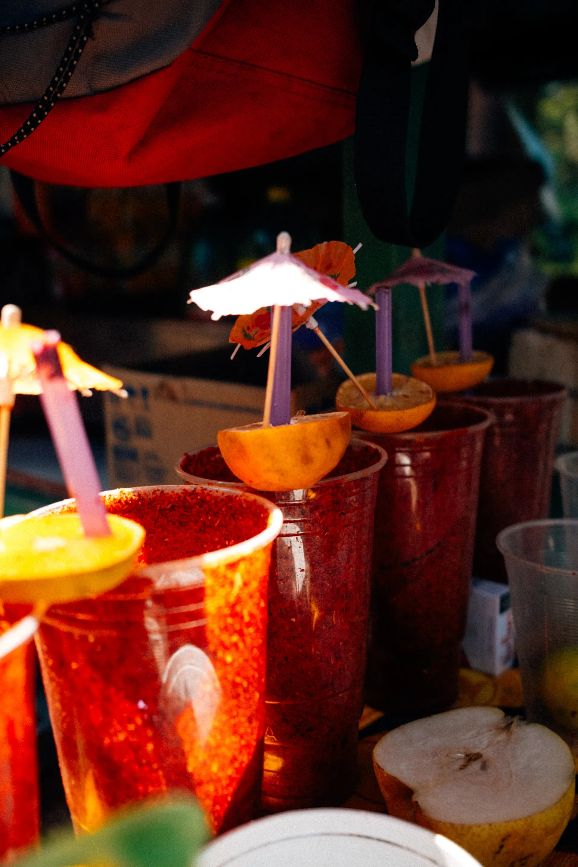 Cups rimmed with chili powder and topped with lemon halves and paper umbrellas at a street stall in Mexico City