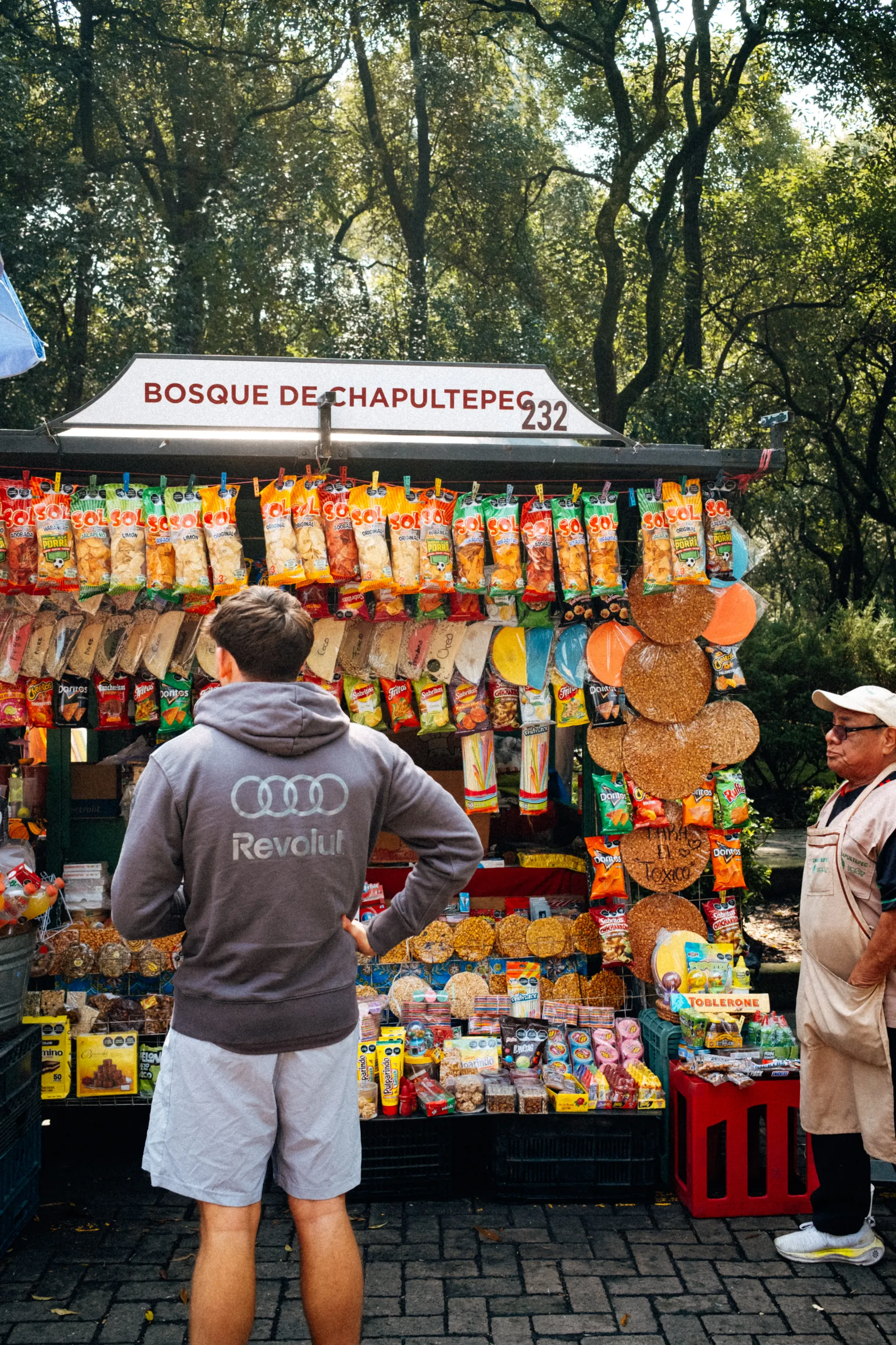 Rear view of Freddie Slater in an Audi Revolut F1® Team hoodie at a snack kiosk in Bosque de Chapultepec