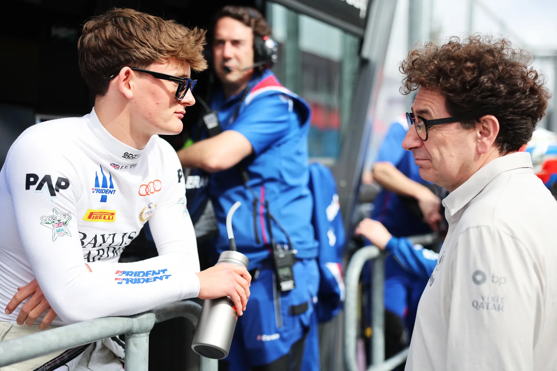 Freddie Slater leaning on a barrier speaking with Mattia Binotto inside the Audi Revolut F1® Team garage during a Formula 3 race weekend