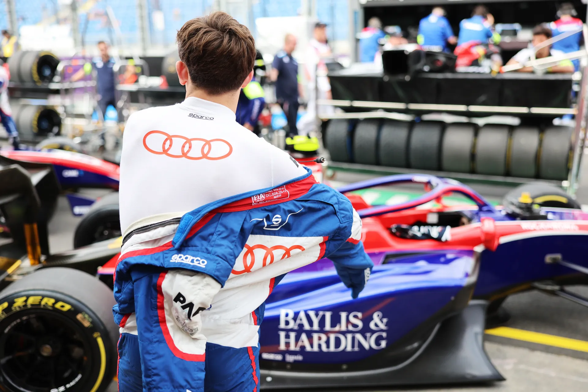 Freddie Slater putting on his race suit in front of his Formula 3 car in the garage
