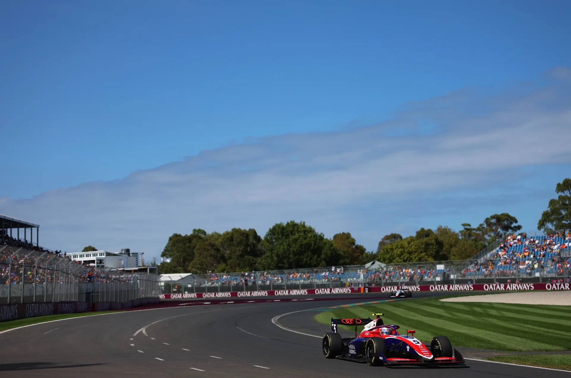 Formula 3 car running on track during race action with grandstands in the background