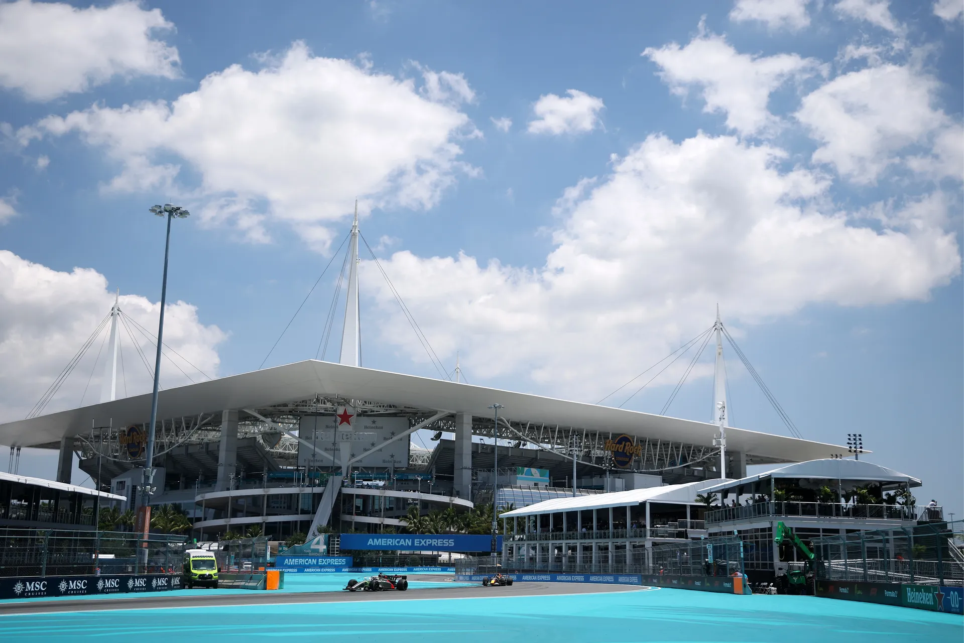 Audi Revolut F1® Team cars racing past Hard Rock Stadium during Miami Grand Prix with turquoise run off areas
