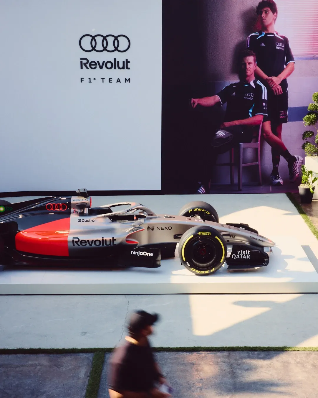 Audi Revolut F1® Team show car displayed at the MAPS Backlot activation in Miami, with a large campaign wall featuring Gabriel Bortoleto and Nico Hulkenberg in the special adidas x Audi Revolut F1® Team Miami collection.
