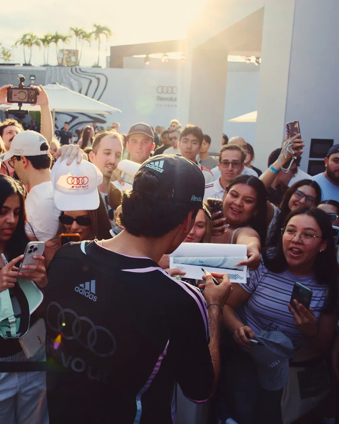 Gabriel Bortoleto signs posters for fans in front of the Audi Revolut F1® Team activation space at MAPS Backlot in Miami.