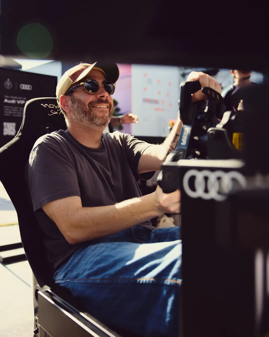Visitor smiling while using a racing simulator at the Audi Revolut F1® Team off track activation at MAPS Backlot in Miami.