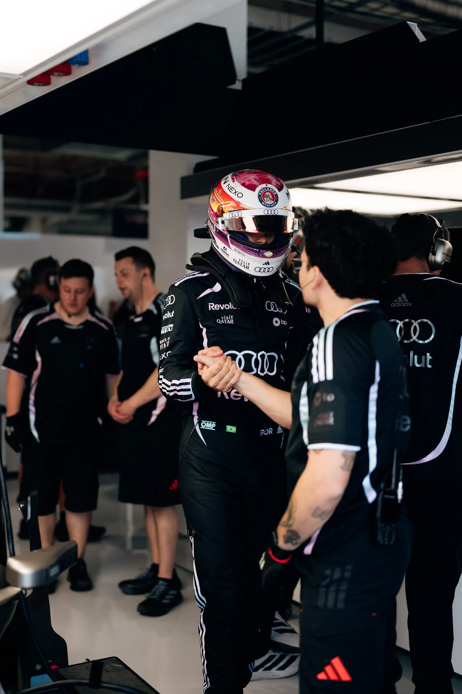 Audi Revolut F1® Team driver Gabriel Bortoleto in a special Miami helmet shakes hands with a team member inside the garage before getting into the car.