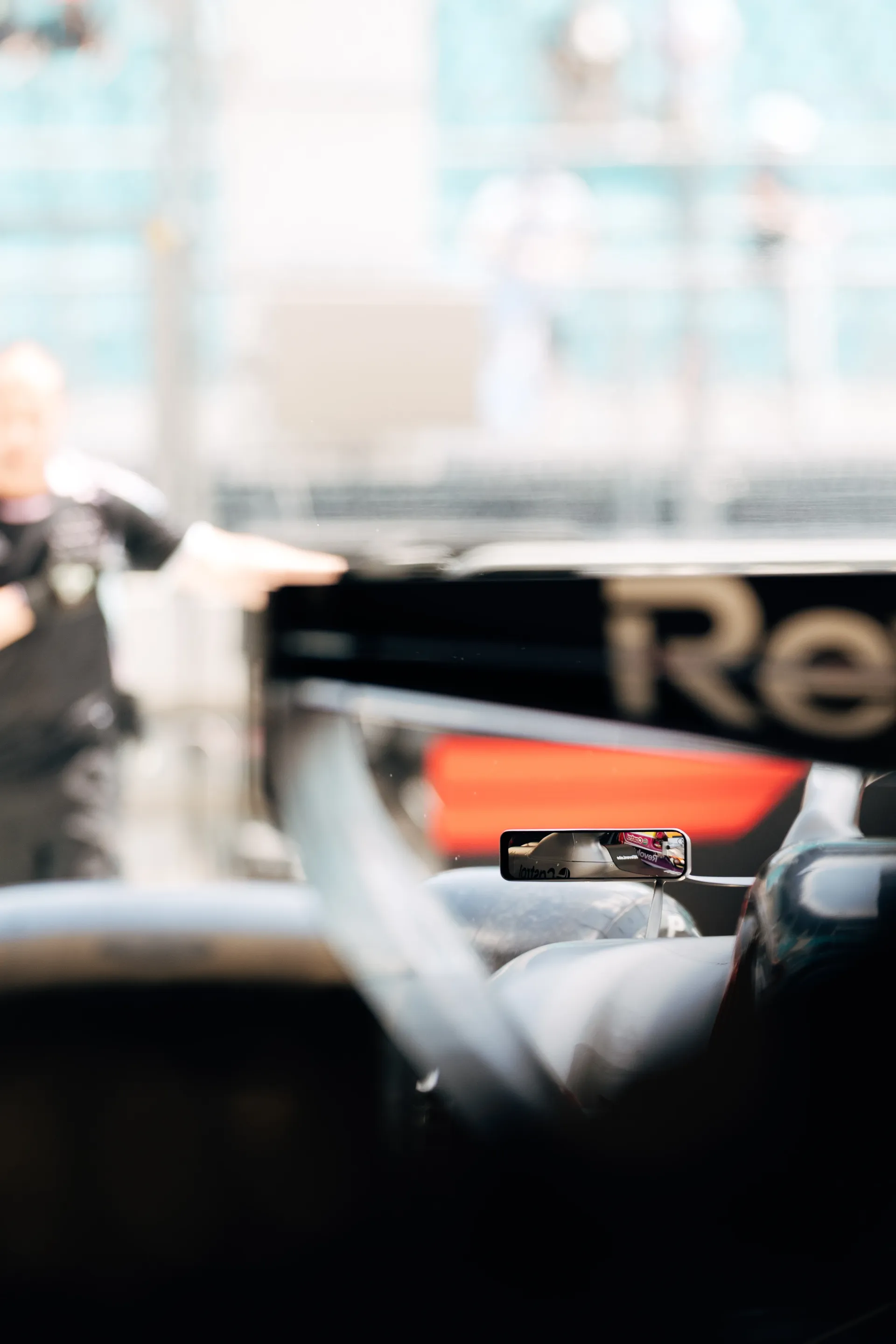 Detail shot of the Audi Revolut F1® Team car in the garage, with Nico Hulkenberg’s helmet reflected in the side mirror.