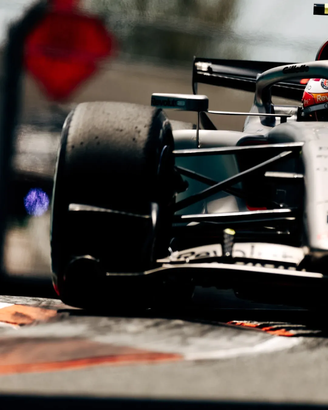Close up of Audi Revolut F1® Team car number 27 with Nico Hulkenberg visible in his orange helmet as the car rides the kerb at speed.