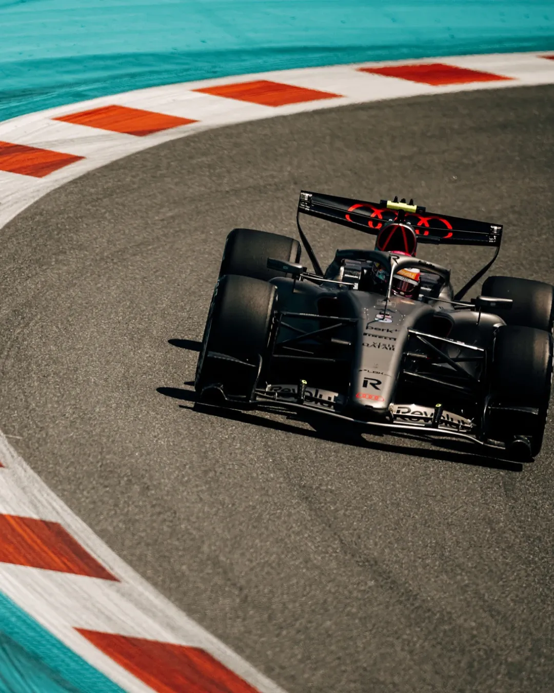 Overhead view of Audi Revolut F1® Team car number 27 driven by Nico Hulkenberg sweeping through a corner framed by Miami’s blue and orange track markings.