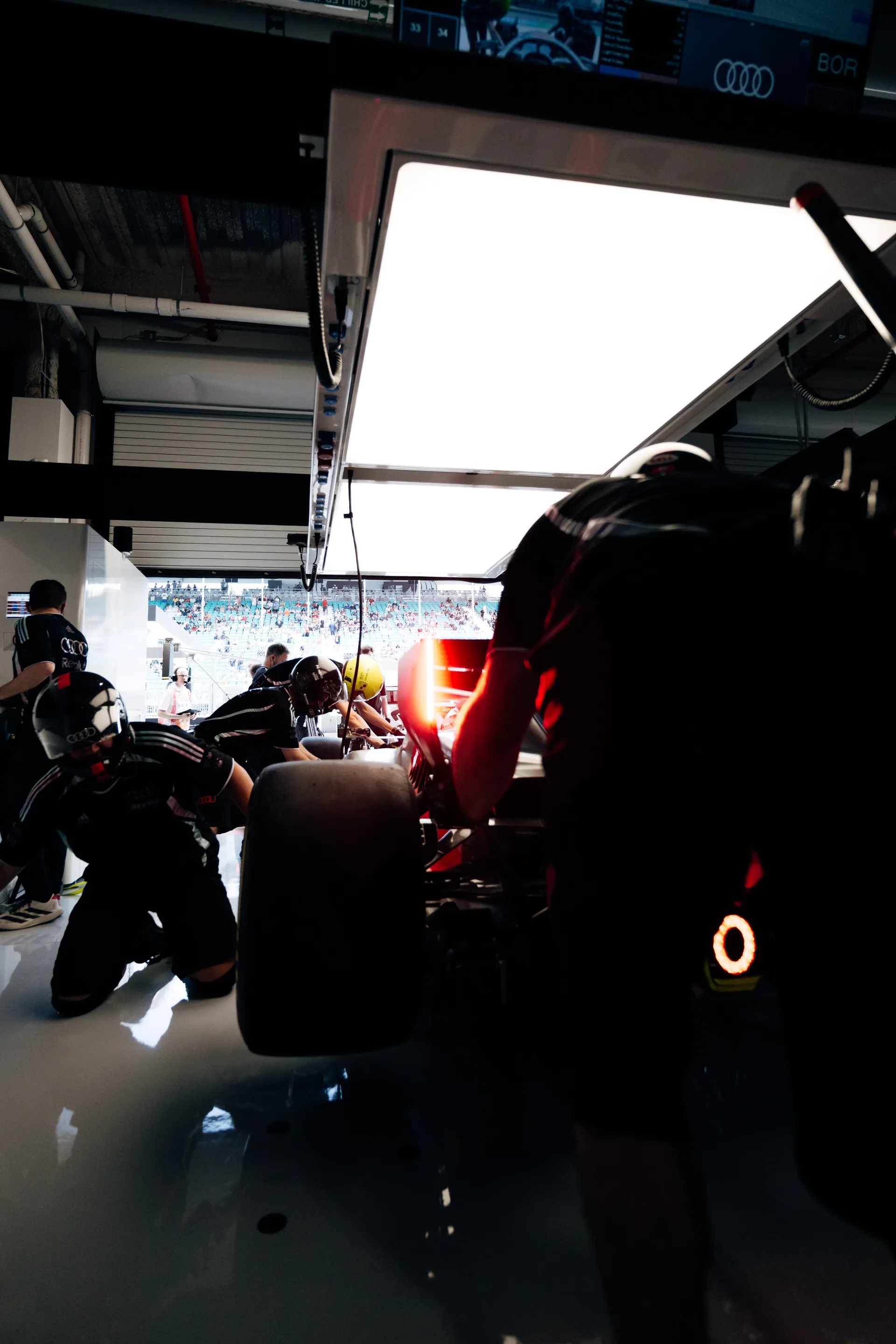 Rear three-quarter garage view of the Audi Revolut F1® Team car as mechanics work around it before heading out.