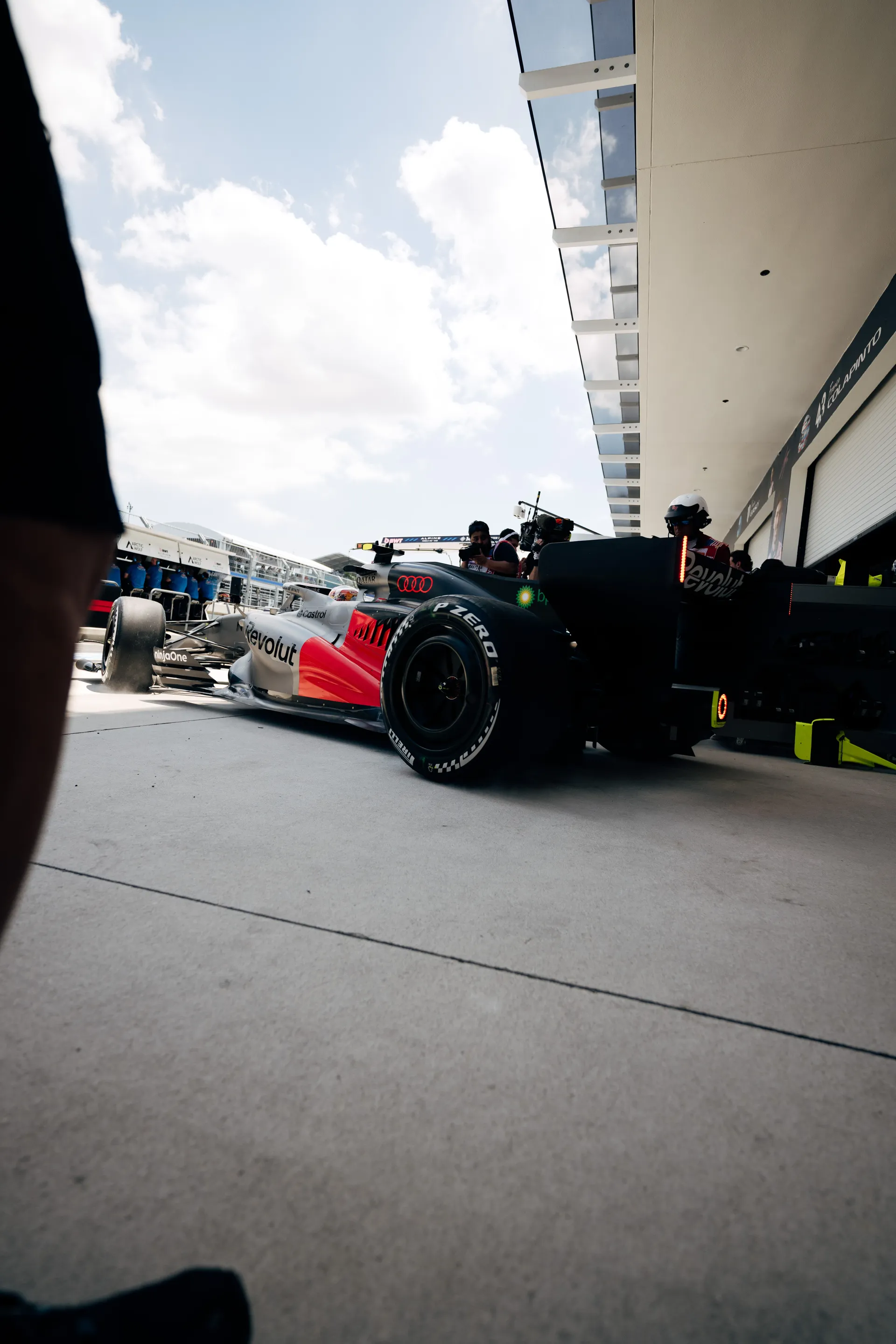Low-angle side view of the Audi Revolut F1® Team car being guided out of the garage into the Miami pit lane.