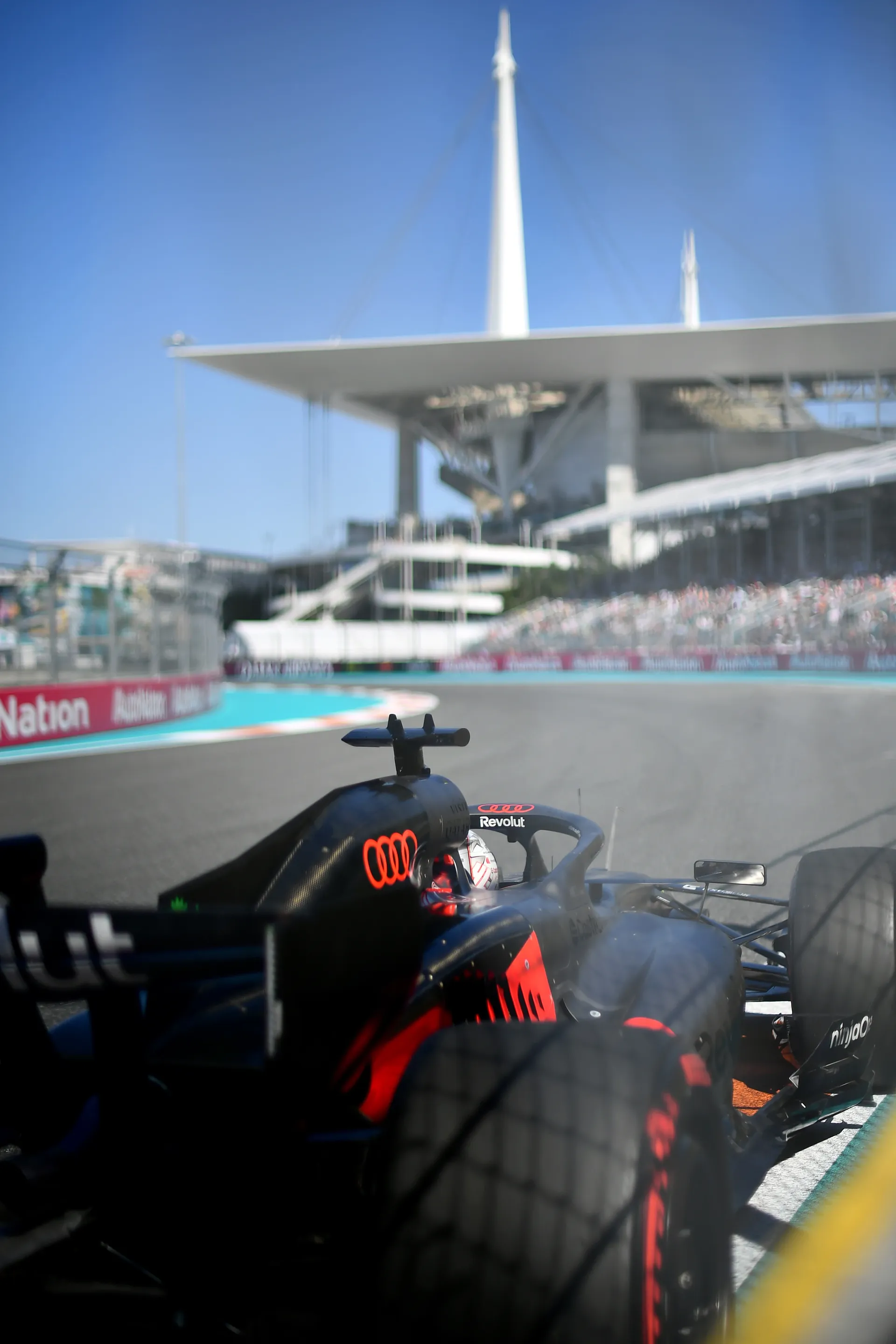 Onboard rear view of Audi Revolut F1® Team car exiting corner at Miami Grand Prix with Hard Rock Stadium in background