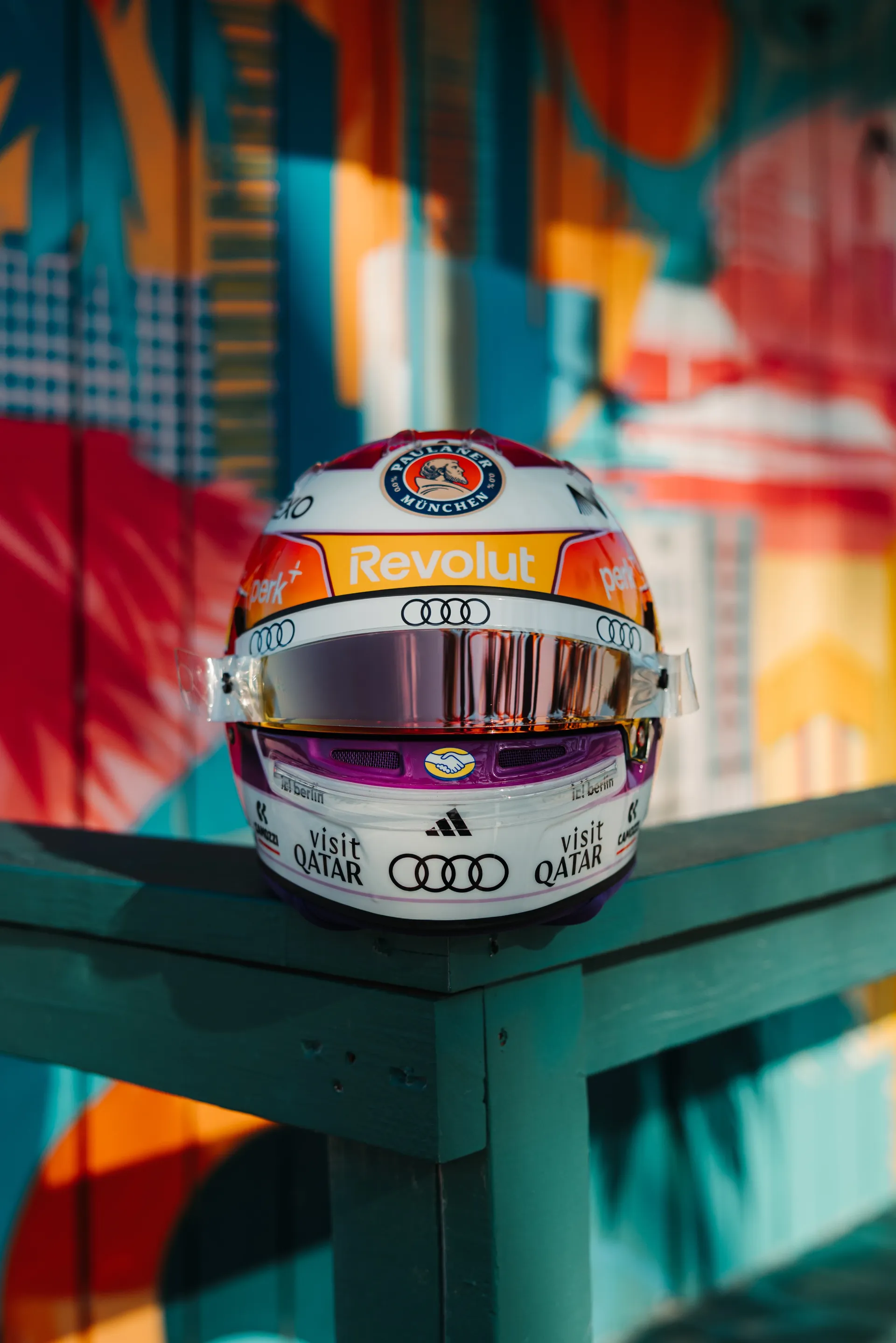 Front view of Gabriel Bortoleto’s special Miami edition race helmet placed on a turquoise lifeguard stand, with a colorful Miami mural in the background.
