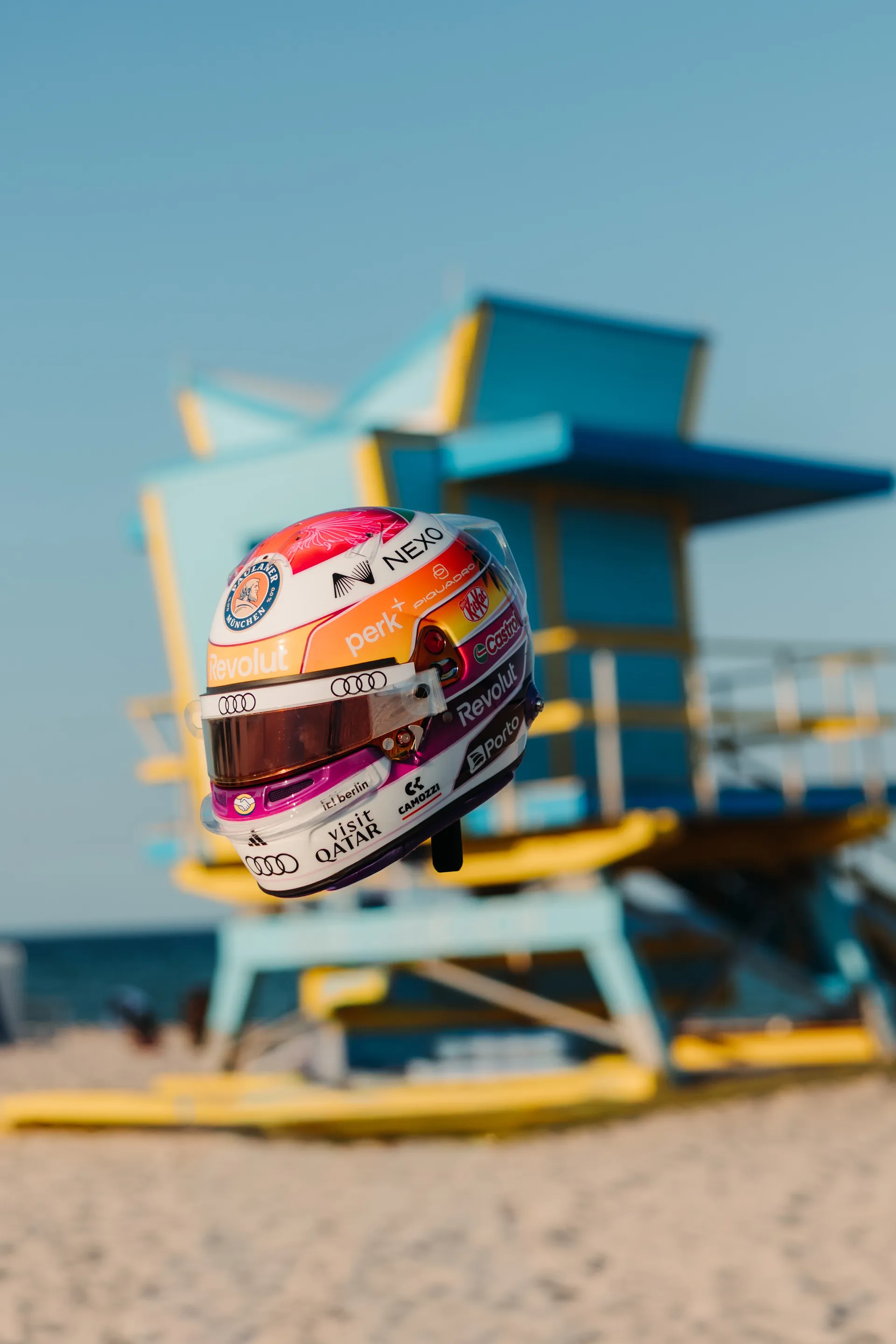 Gabriel Bortoleto’s special Miami edition race helmet floating in front of a pastel blue and yellow lifeguard tower on Miami Beach.