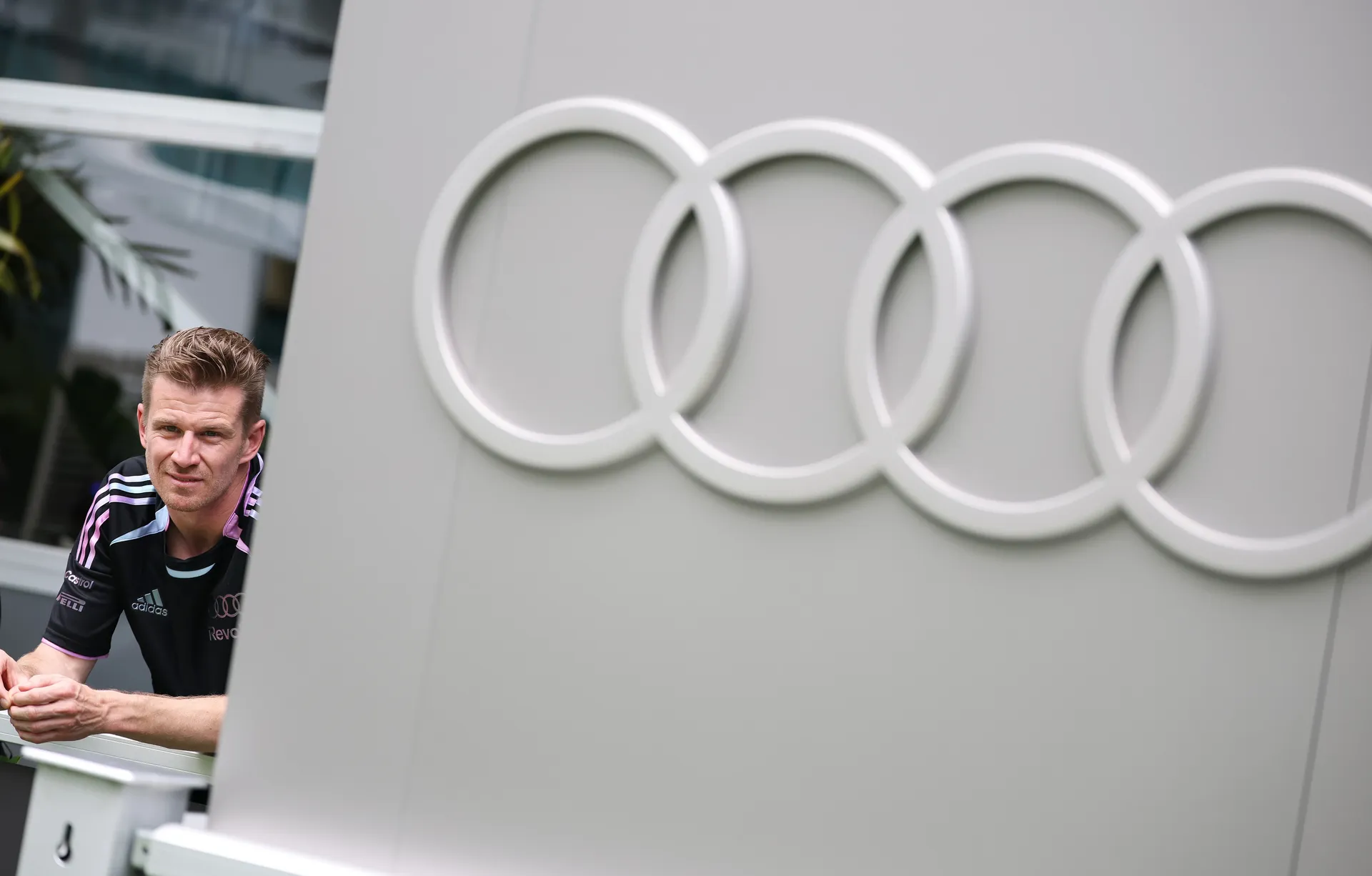 Nico Hulkenberg leaning against a balcony with Audi logo in the background during Audi Revolut F1® Team media day in Miami
