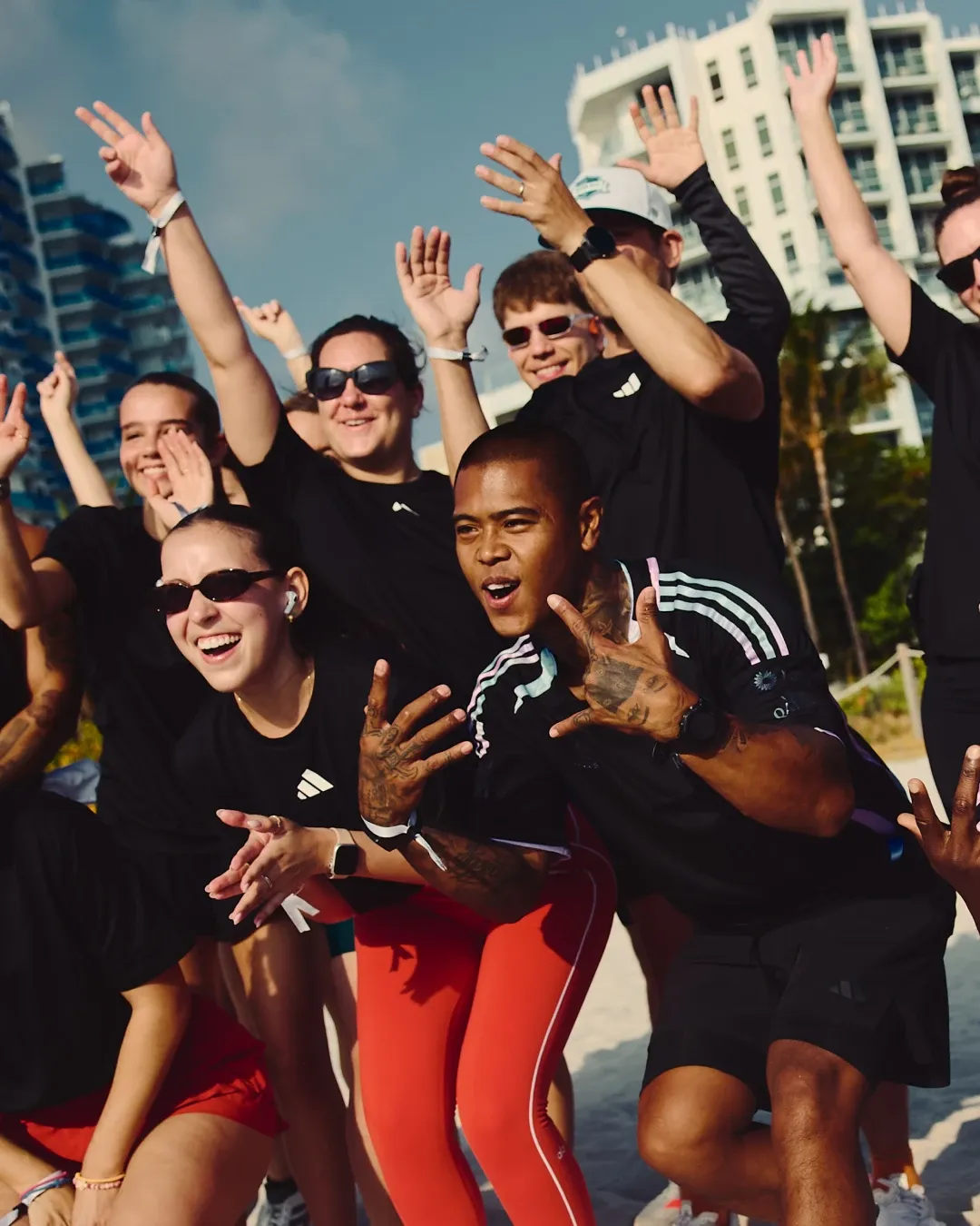 Group of runners celebrates together on the beach during the adidas social run, wearing the special adidas Audi Revolut F1® Team Miami collection.