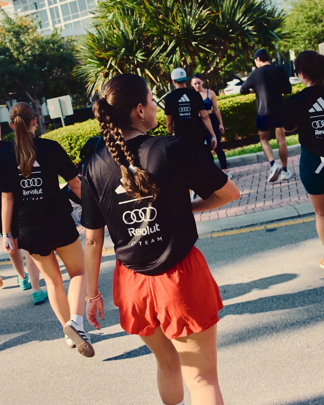 Group of participants walks together through Miami streets during the adidas social run, all wearing the special adidas Audi Revolut F1® Team Miami collection.