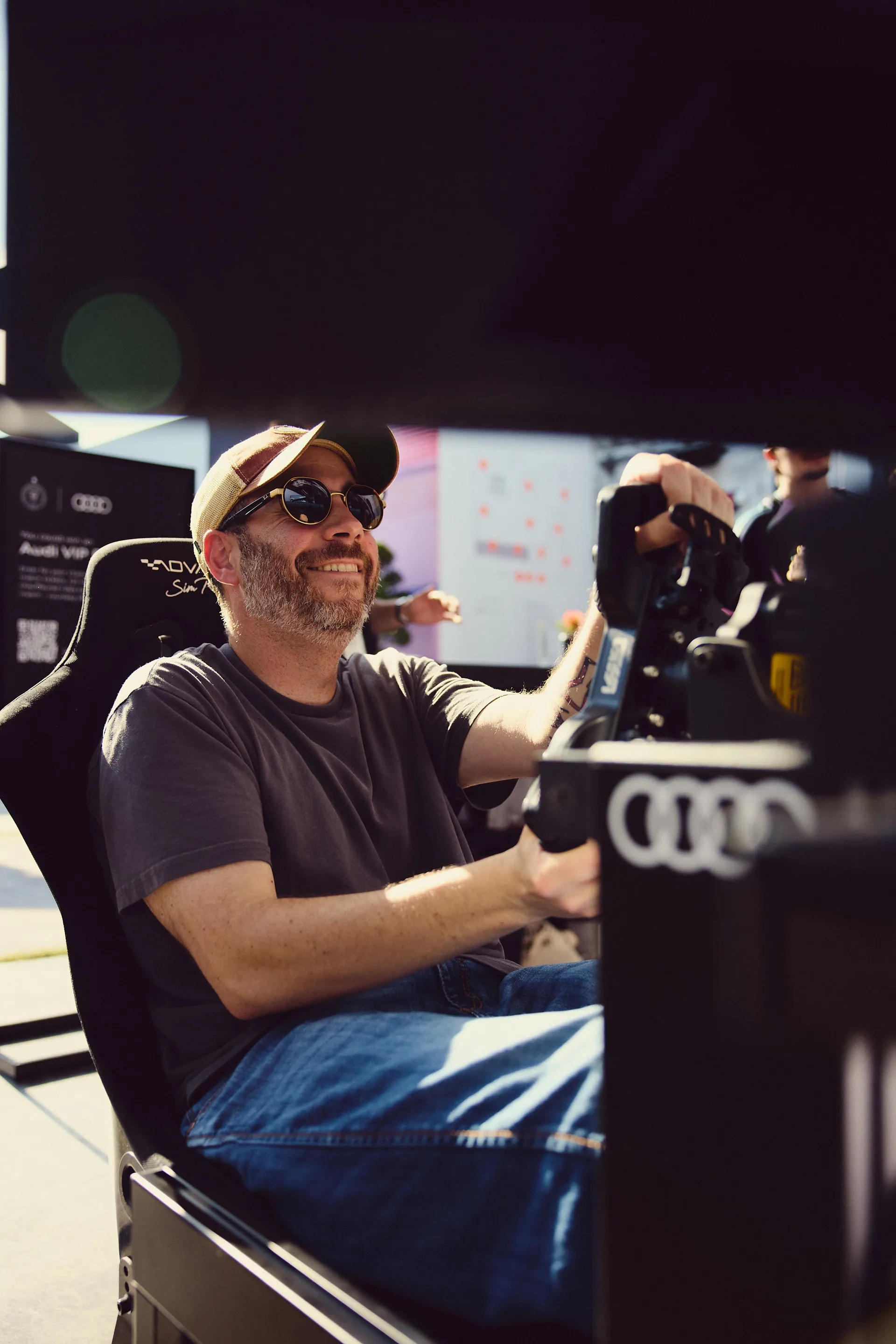 Fan using a racing simulator at the Audi Revolut F1® Team Miami activation, smiling while engaging with interactive brand experience.