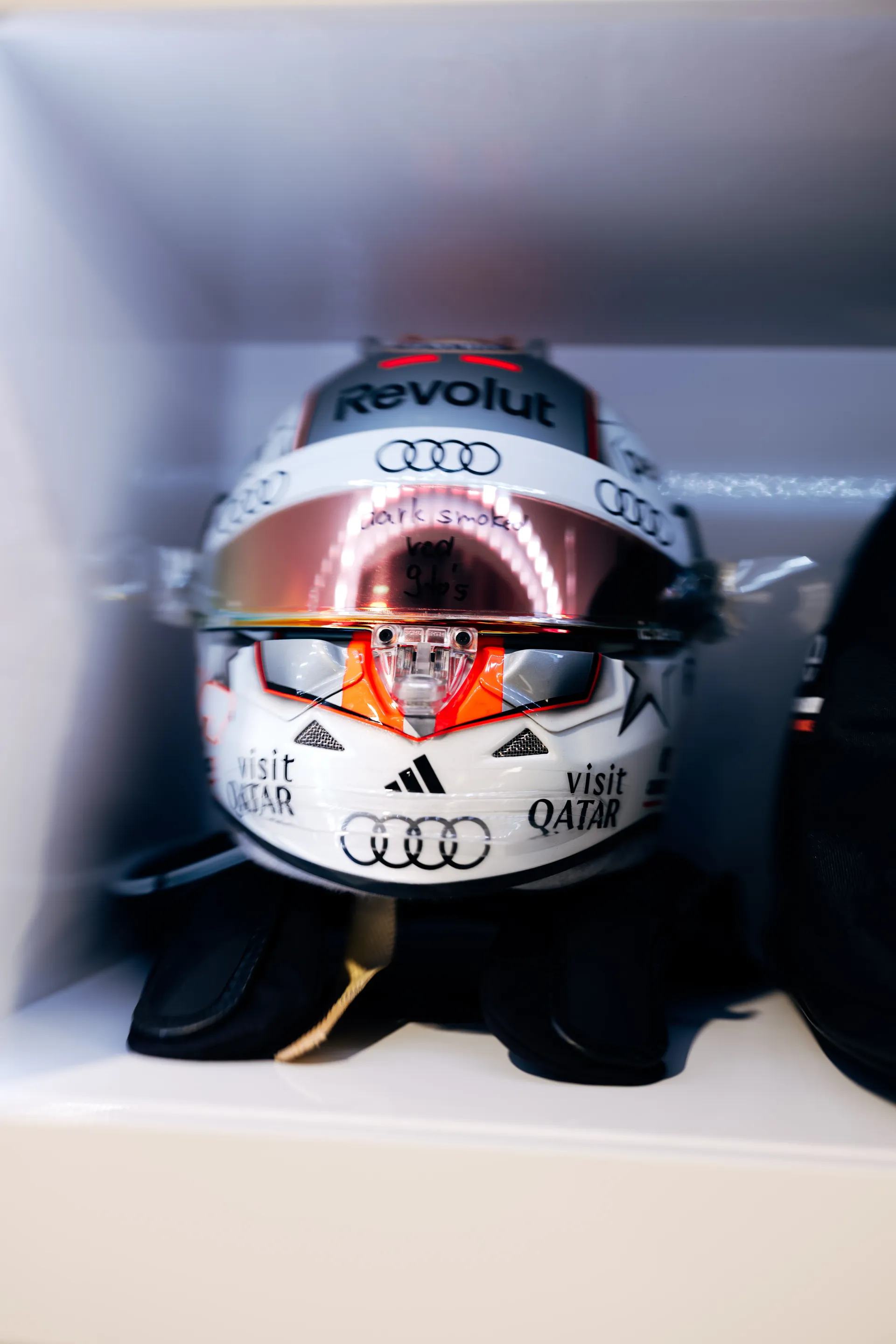 Close-up of Nico Hulkenbergs Audi Revolut F1® Team racing helmet with sponsor logos placed on a shelf inside the garage