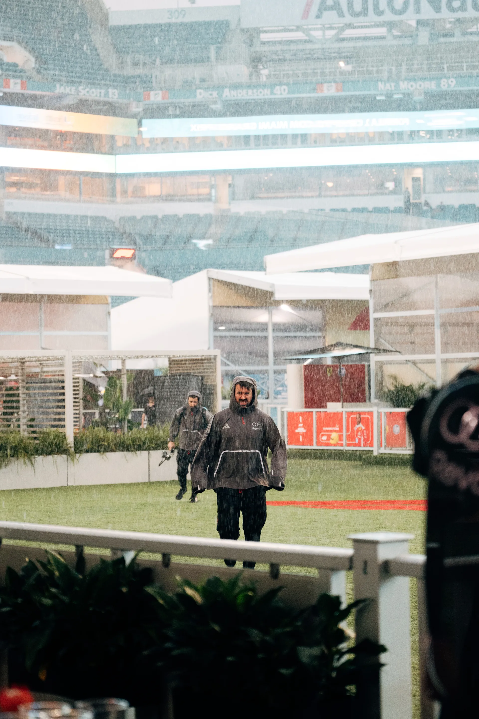 Audi Revolut F1® Team crew members walk through heavy rain in the Miami paddock area during the 2026 Miami Grand Prix.