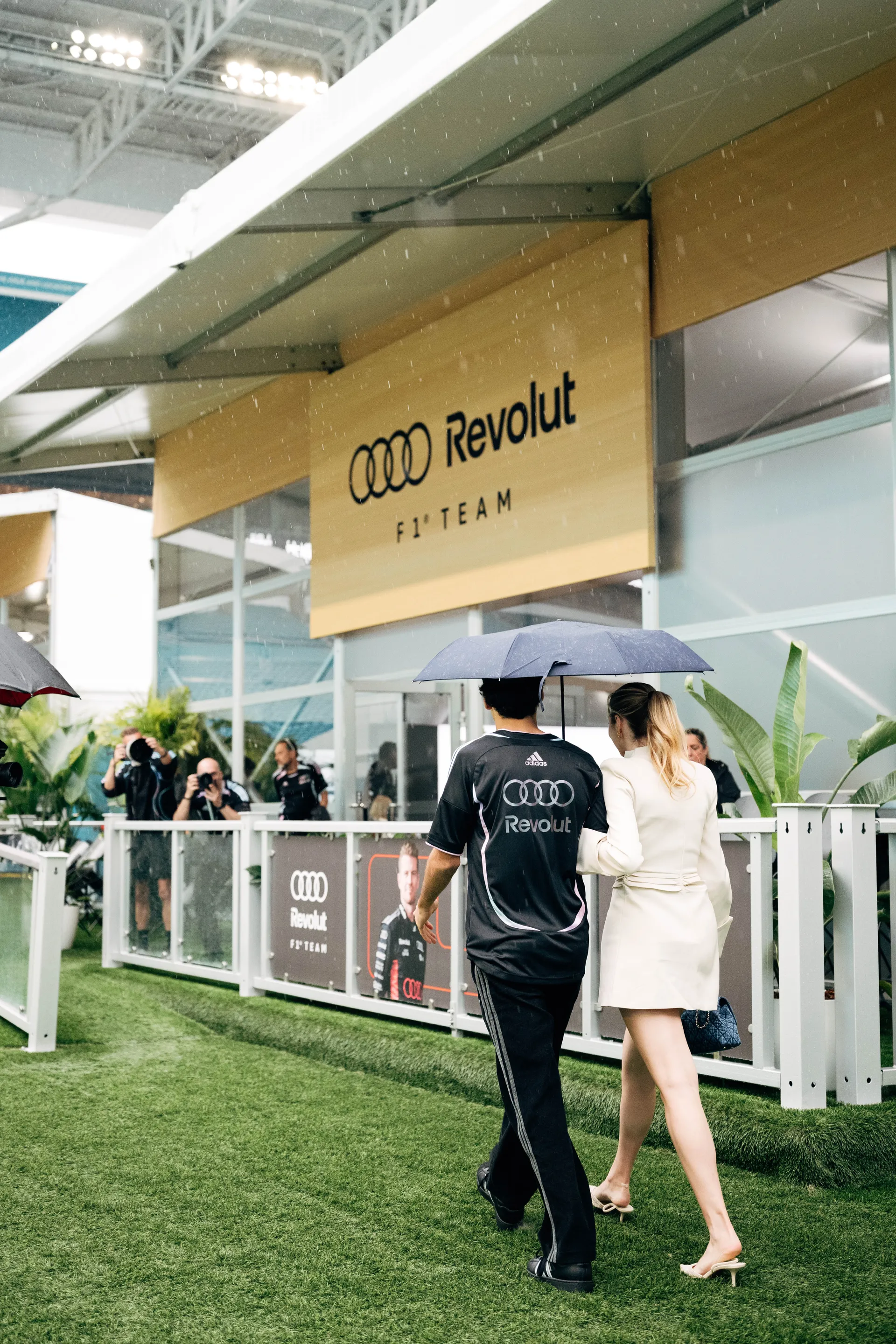 Gabriel Bortoleto walks towards the Audi Revolut F1® Team hospitality area in Miami during rainy conditions at the 2026 Grand Prix weekend.