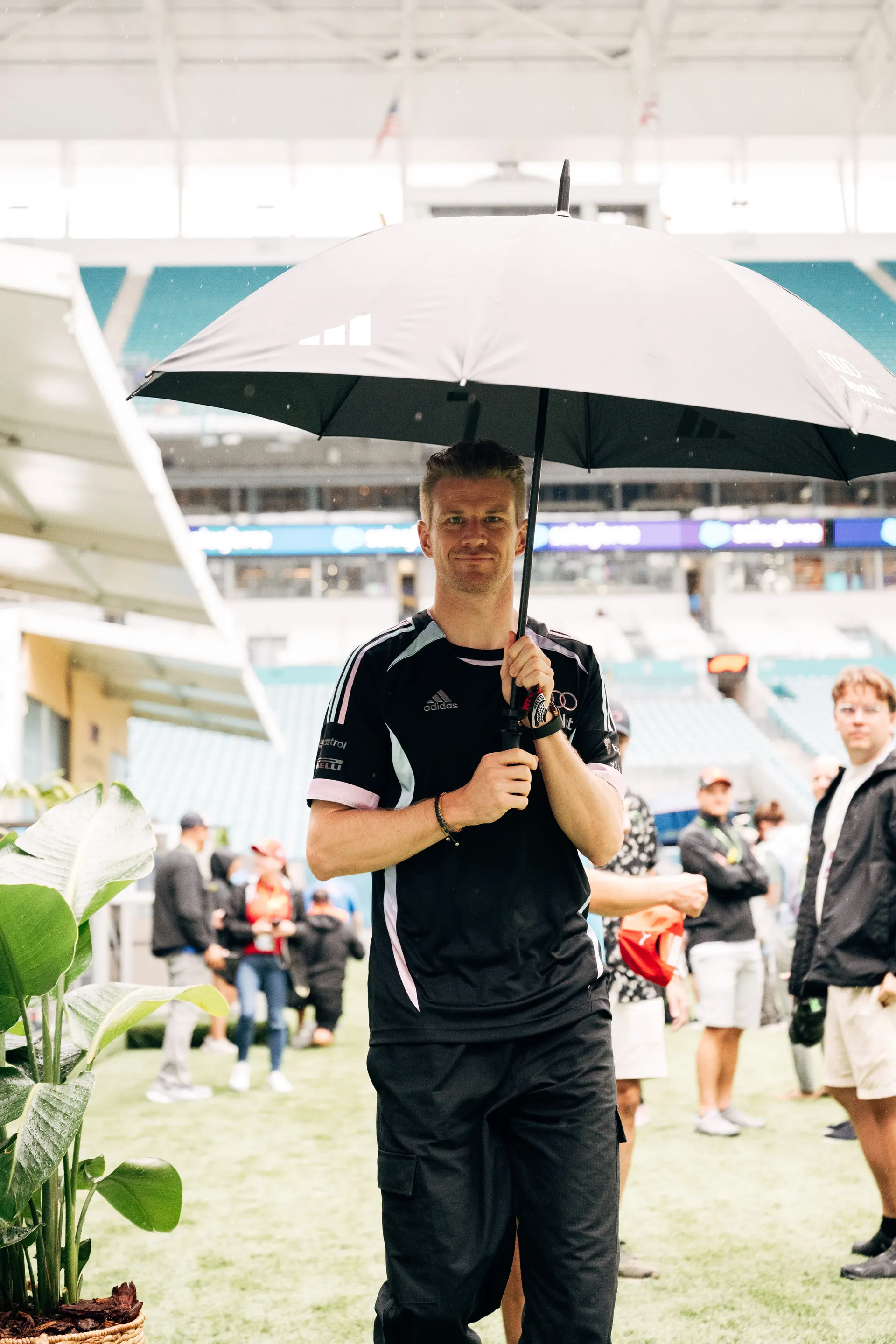 Nico Hulkenberg arrives holding an umbrella in the Miami paddock as Audi Revolut F1® Team prepares for the 2026 Miami Grand Prix.