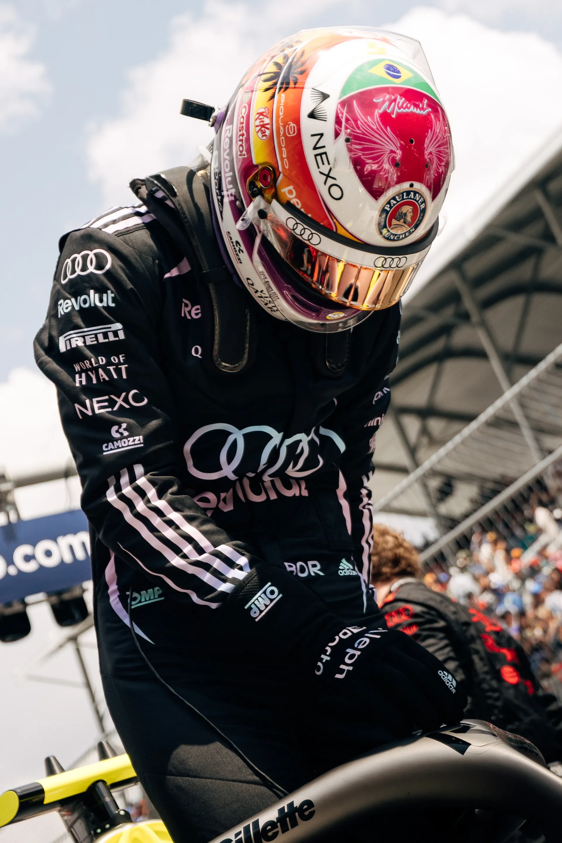 Gabriel Bortoleto in full Audi Revolut F1® Team race suit and helmet leans forward on the car during pre race preparations.