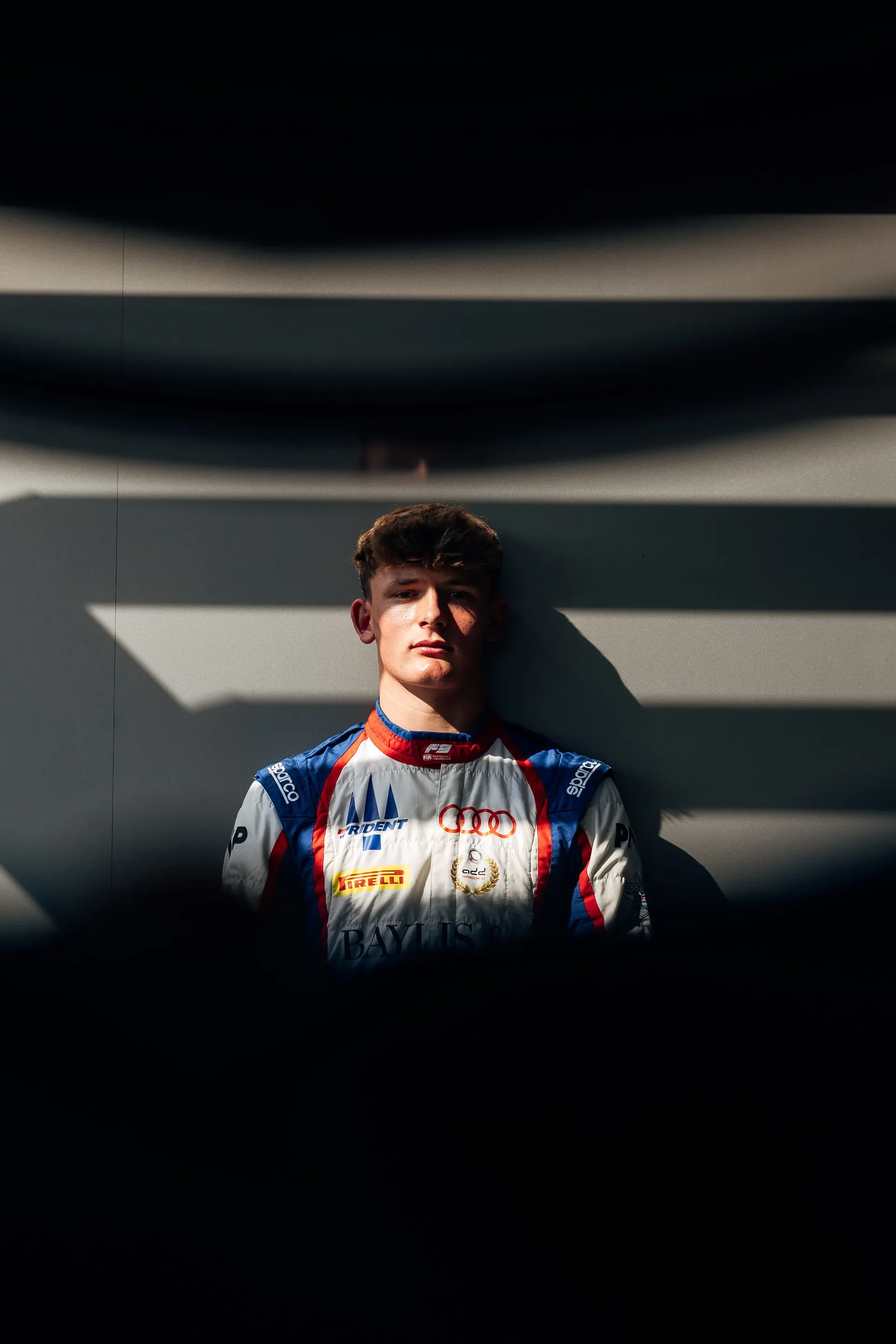 Freddie Slater in his race suit looking into the camera, framed by shadow