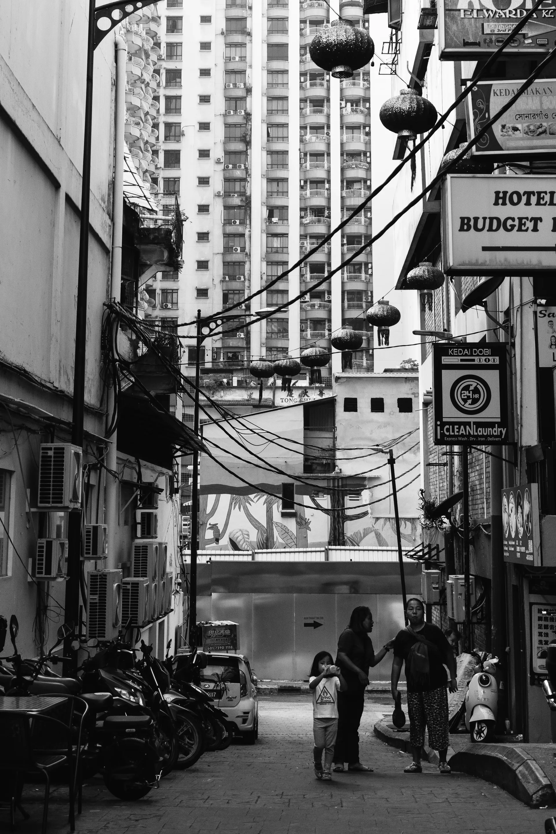 Black and white view of an alley with lanterns and pedestrians in Kuala Lumpur