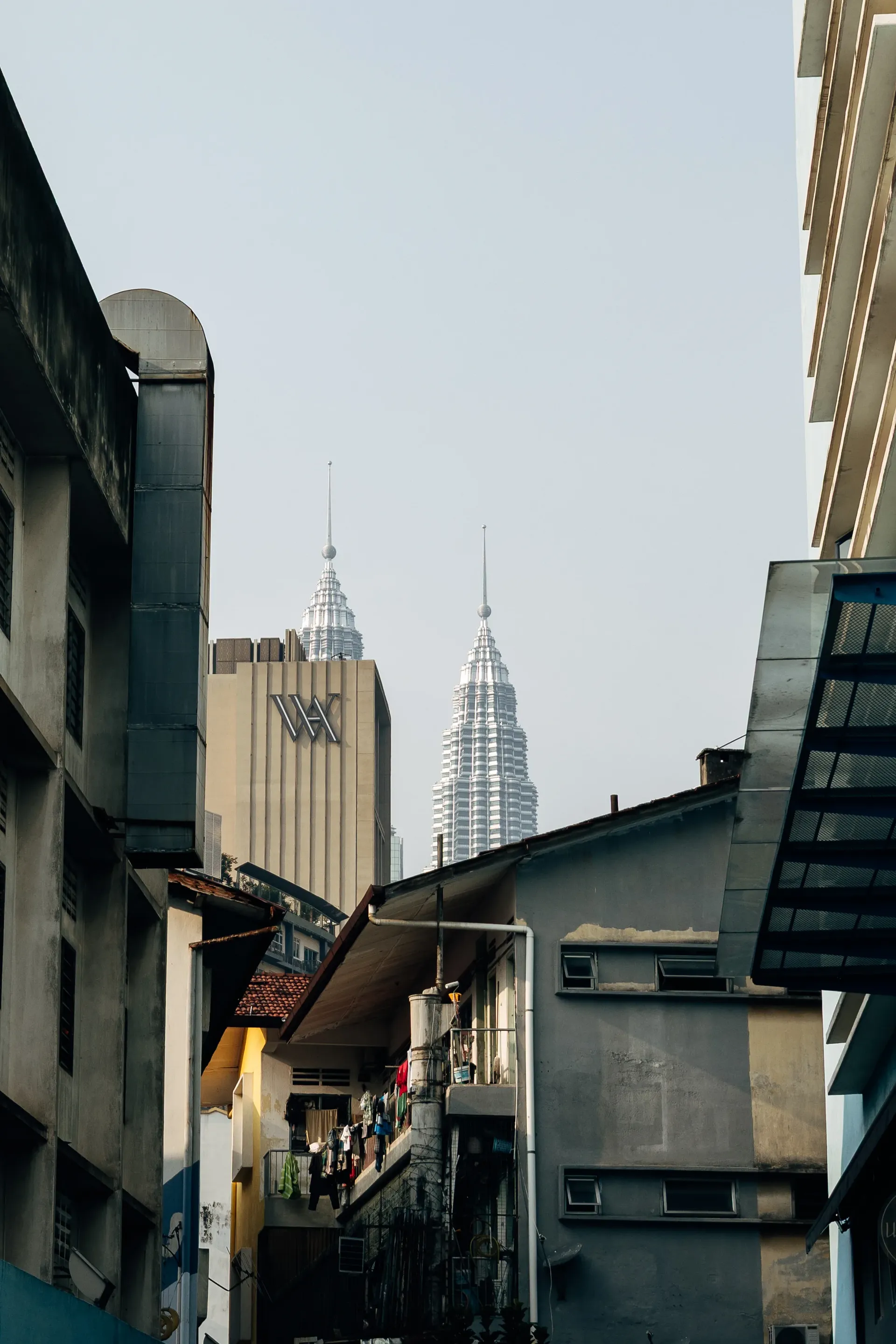 Petronas Towers seen between older buildings in a Kuala Lumpur side street