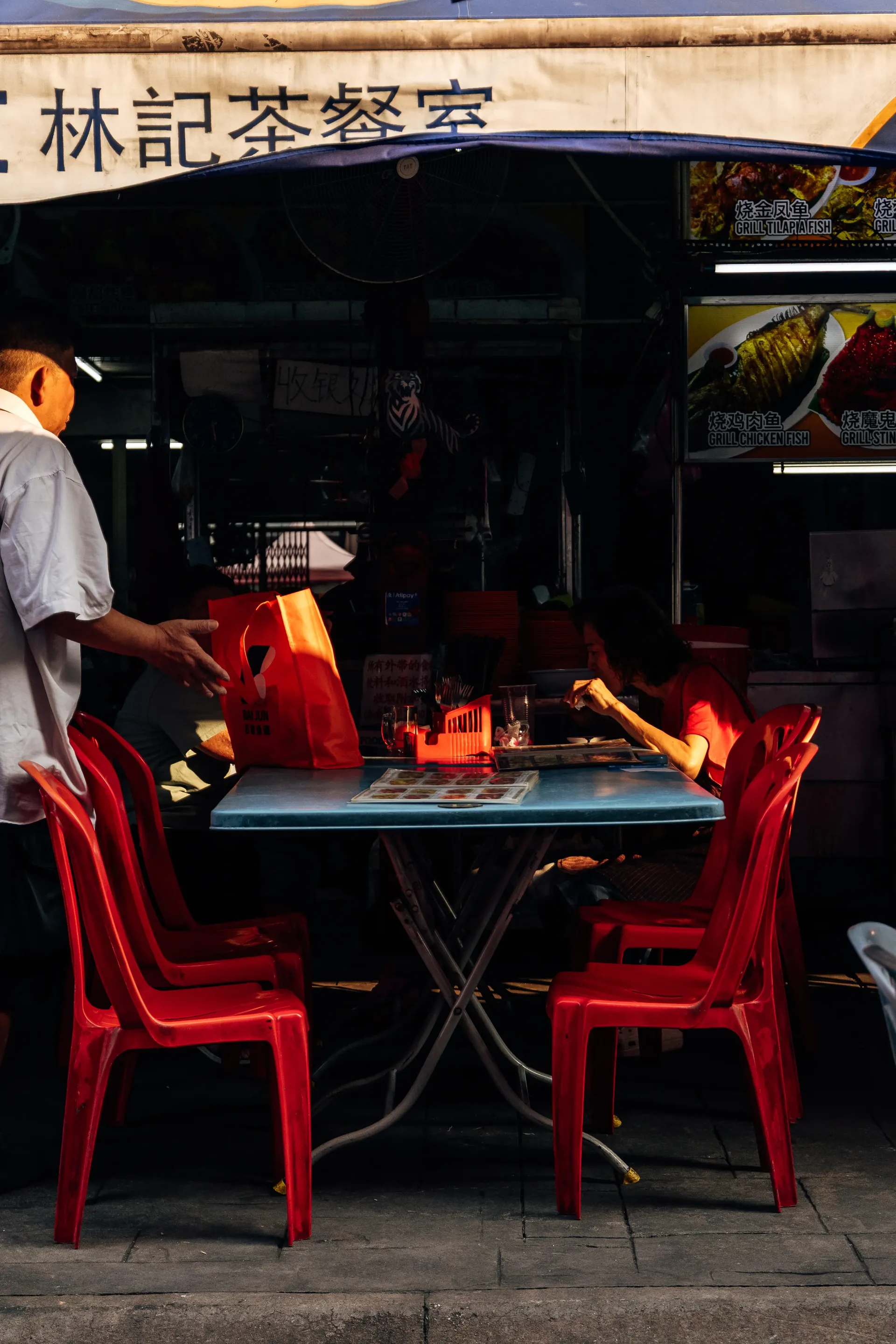 Outdoor table with red plastic chairs at a street restaurant in Kuala Lumpur