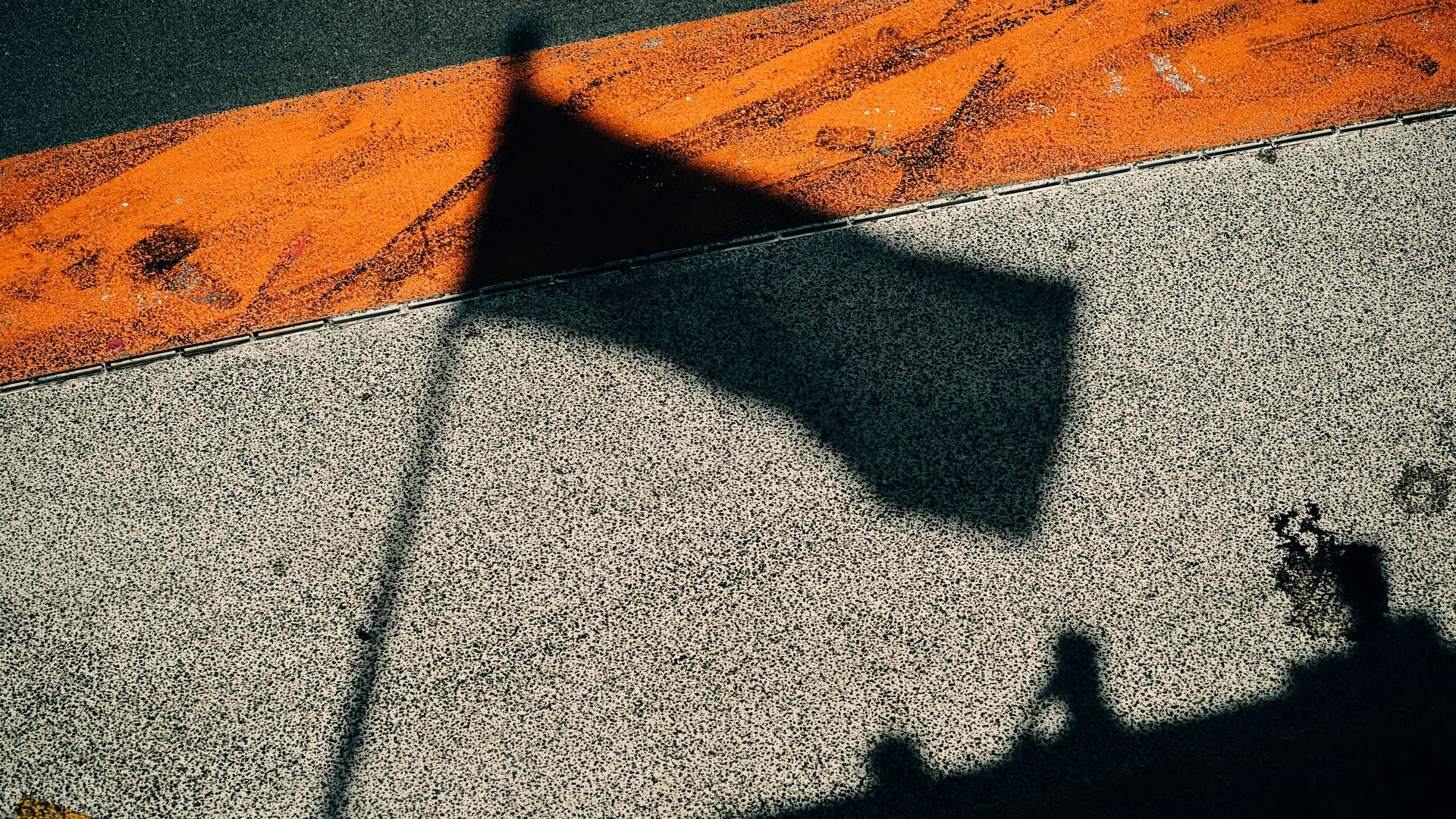 Close-up of shadow patterns on an orange racetrack curb — Audi Revolut F1 Team circuit detail at Zandvoort