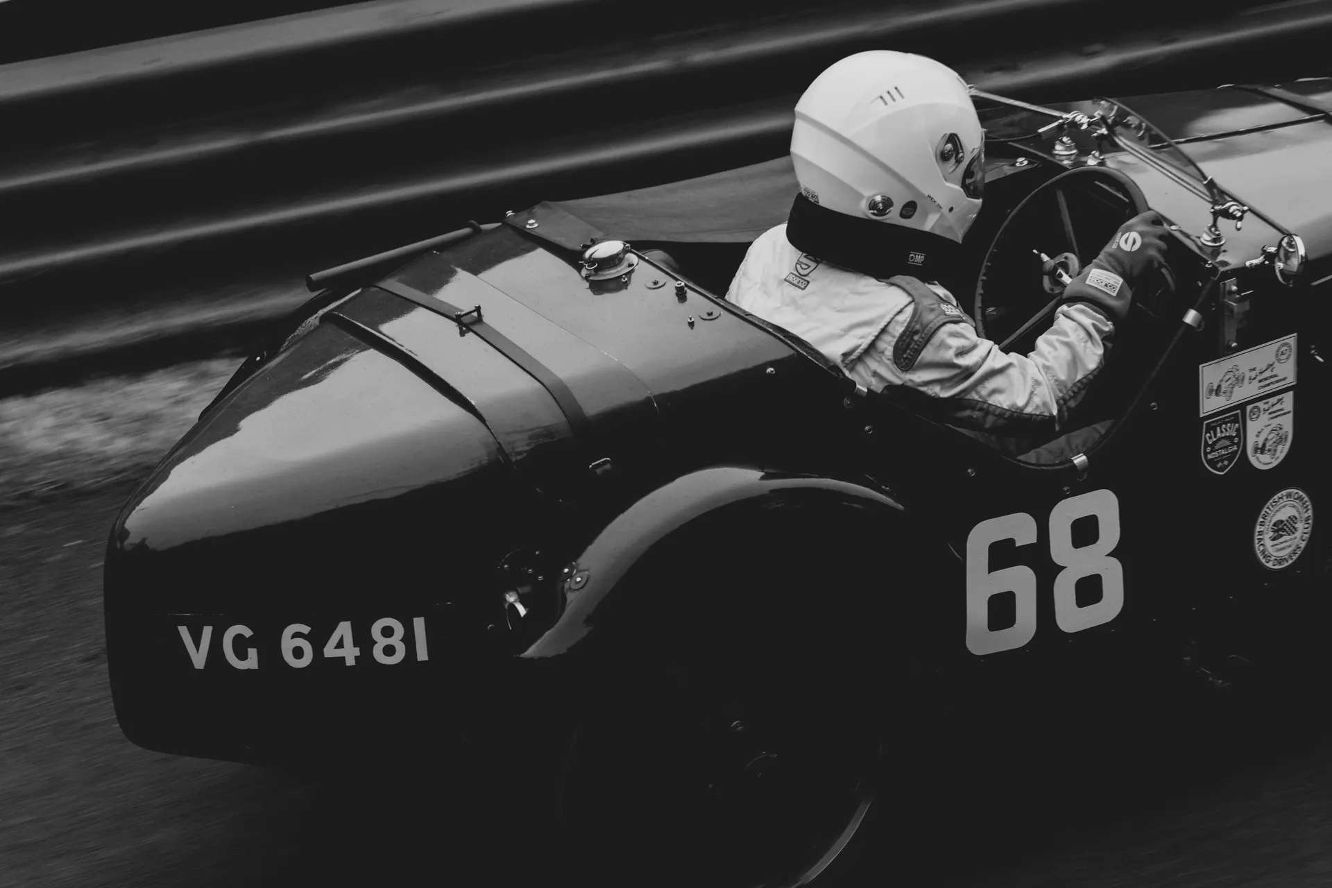 Vintage race car number 68 driven at speed with helmeted driver — Audi Revolut F1 Team classic motorsport spirit