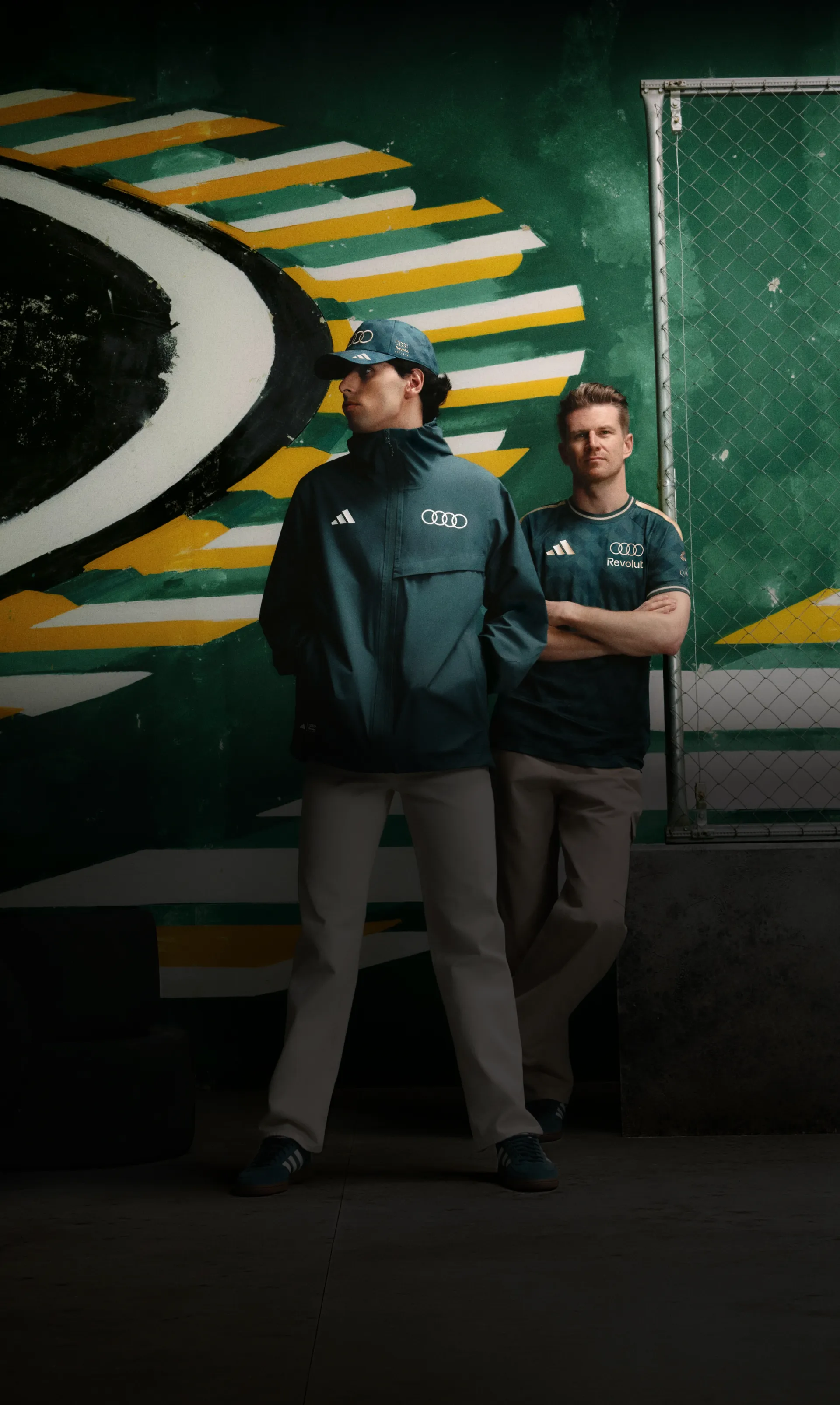 Nico Hulkenberg and Gabriel Bortoleto drivers at the Audi Revolut F1® Team side by side in front of a green and yellow mural, adidas x Audi Revolut F1® Team Sampa Soul collection