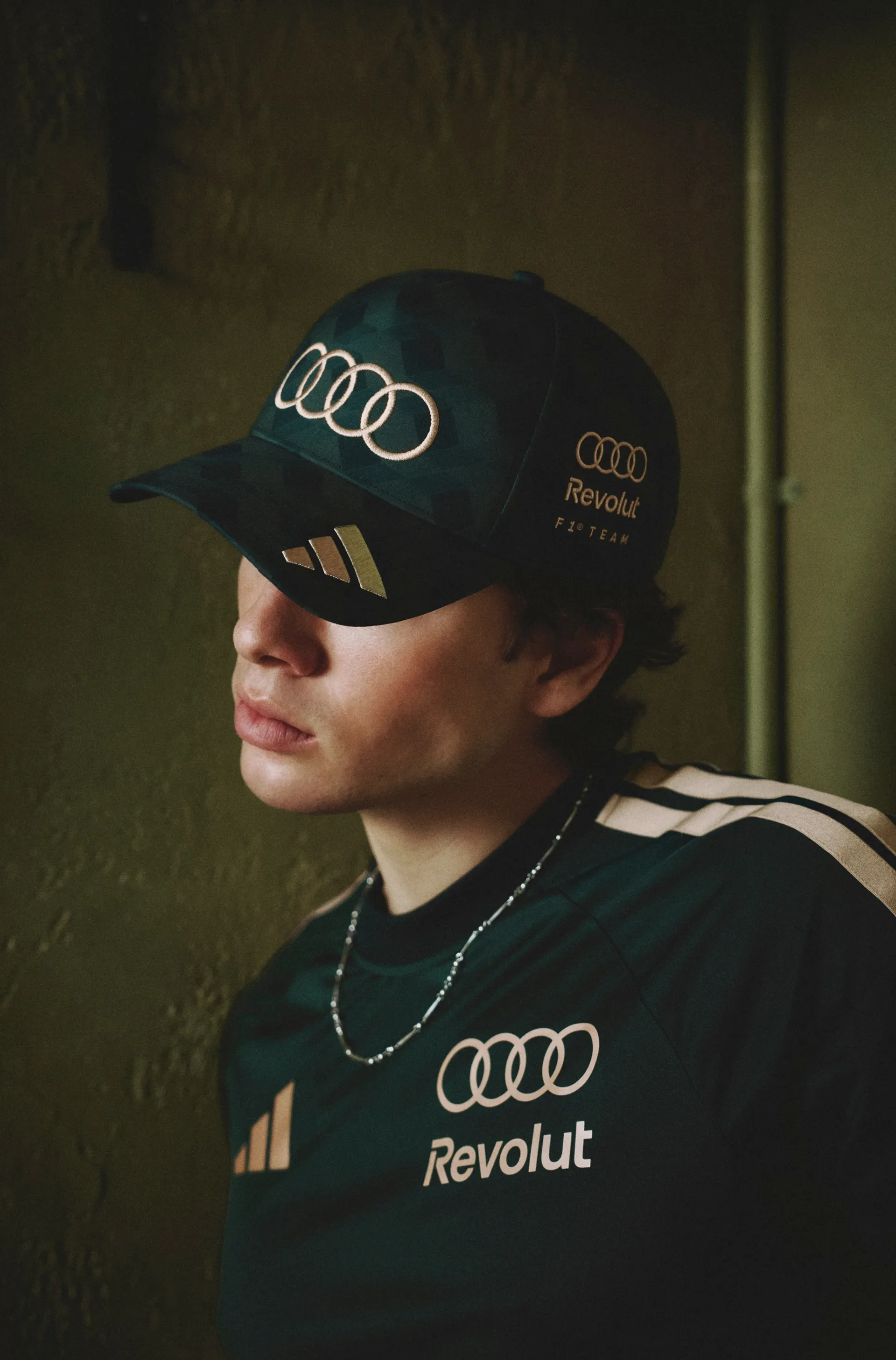 Close-up of a model in the adidas x Audi Revolut F1® Team São Paulo cap and top with three stripes on the shoulder