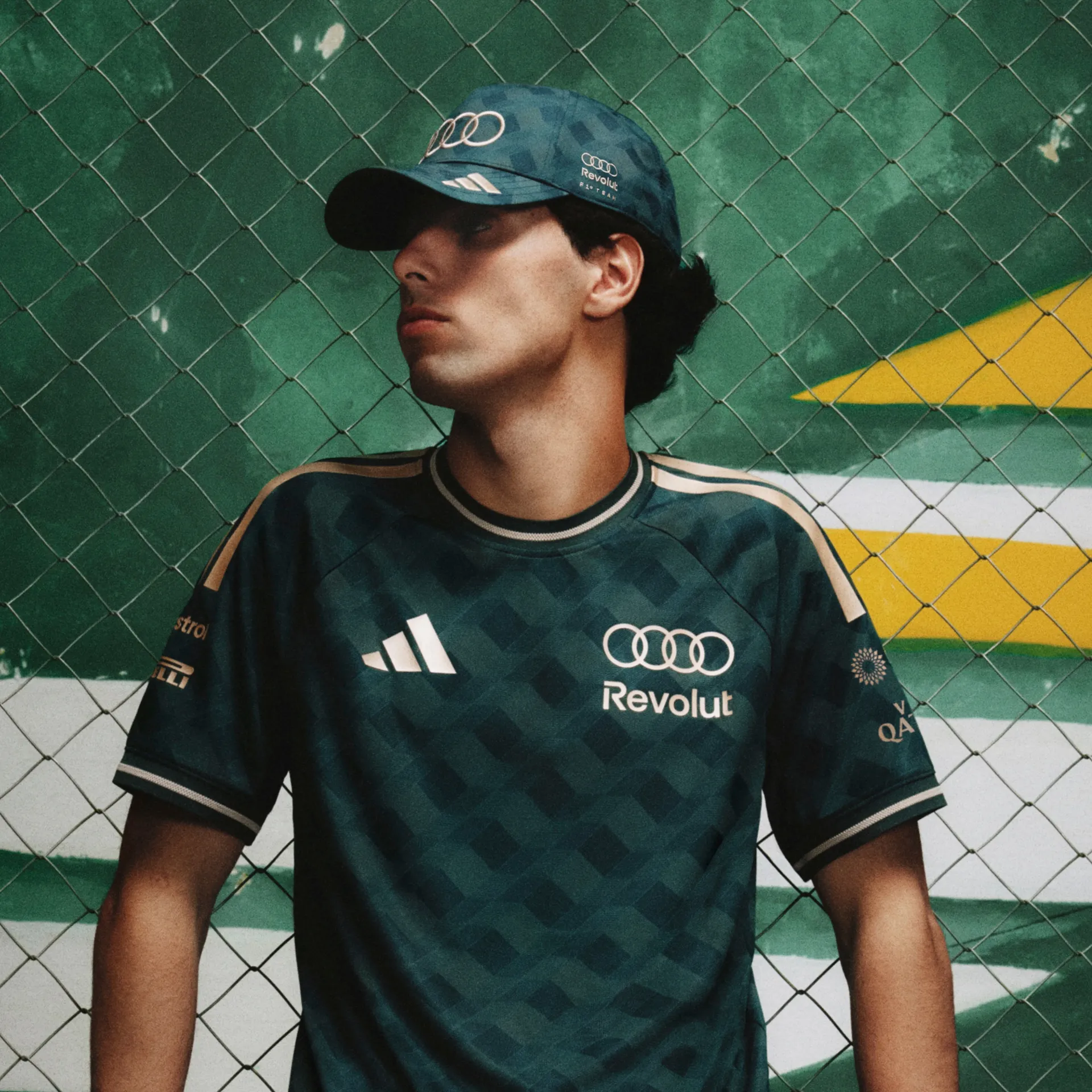 Model in the adidas x Audi Revolut F1® Team São Paulo jersey and cap in front of a green and yellow wall