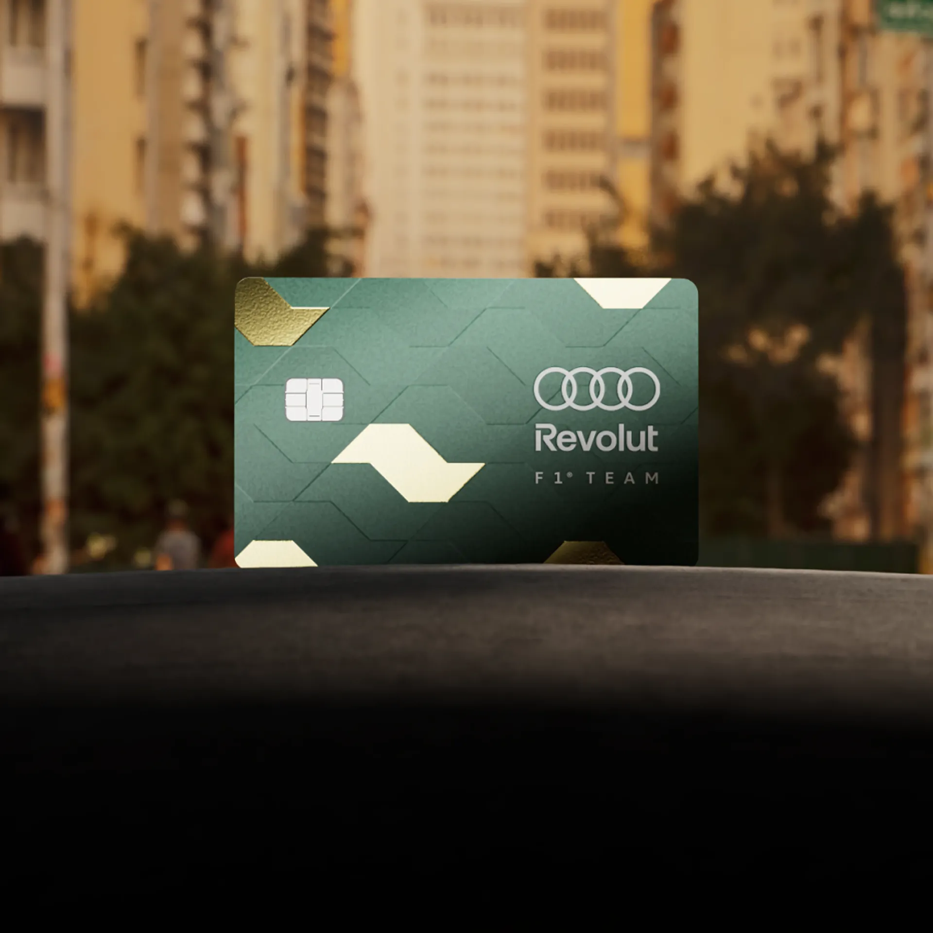 Green Audi Revolut F1® Team Revolut Apex Card standing on a dark surface in front of city high-rises at sunset