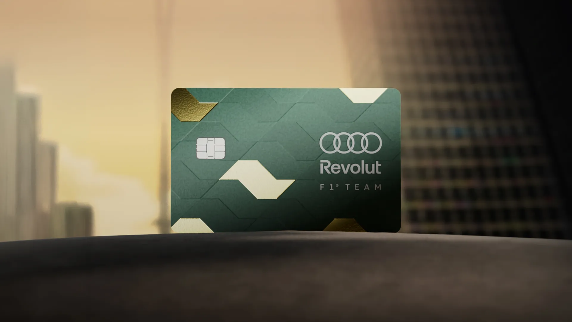 Green Audi Revolut F1® Team Sao Paulo Card standing on a dark surface in front of city high-rises at sunset