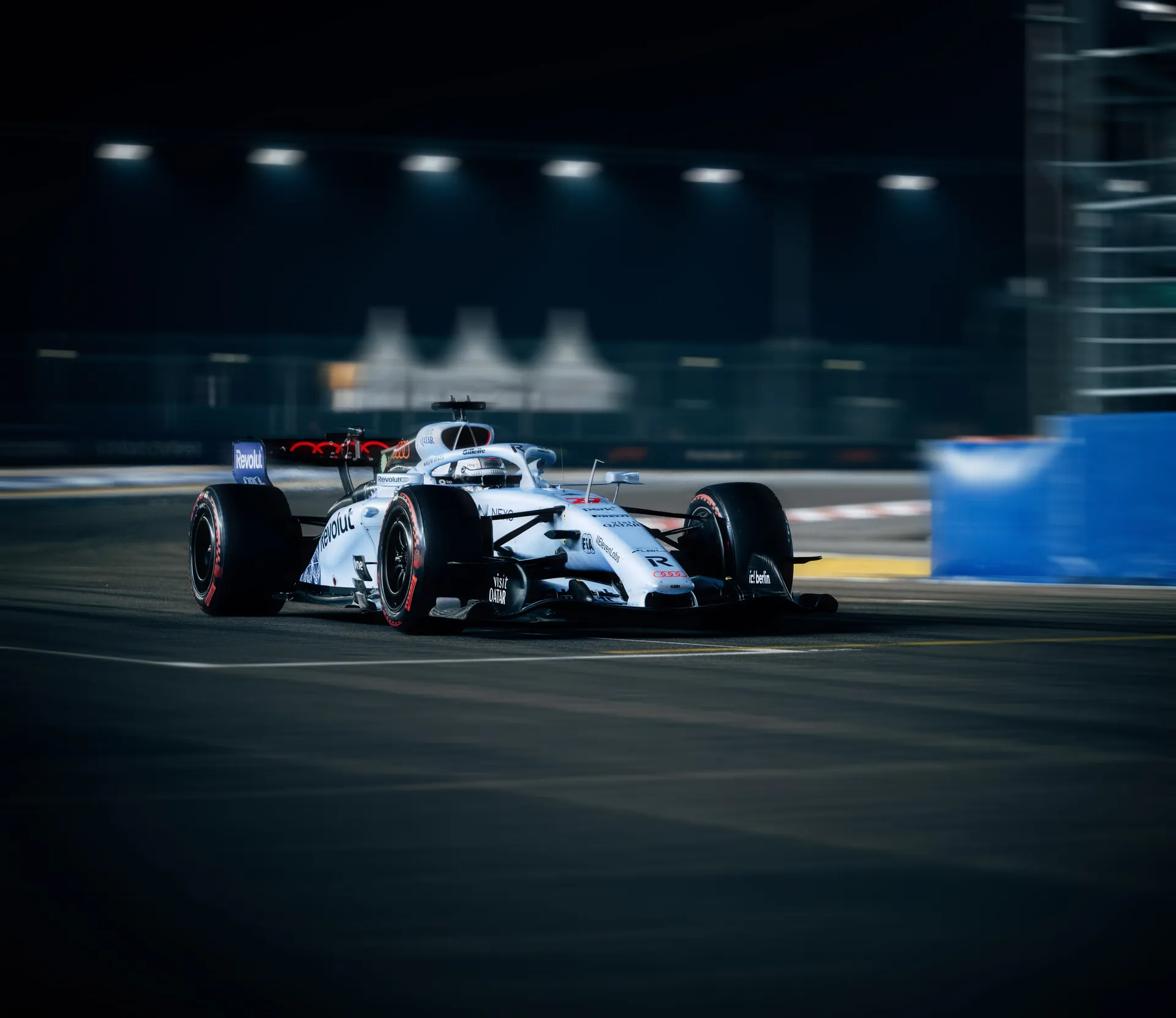 Audi Revolut F1® Team car R26 on track at night at the Singapore Grand Prix, lit by trackside floodlights.
