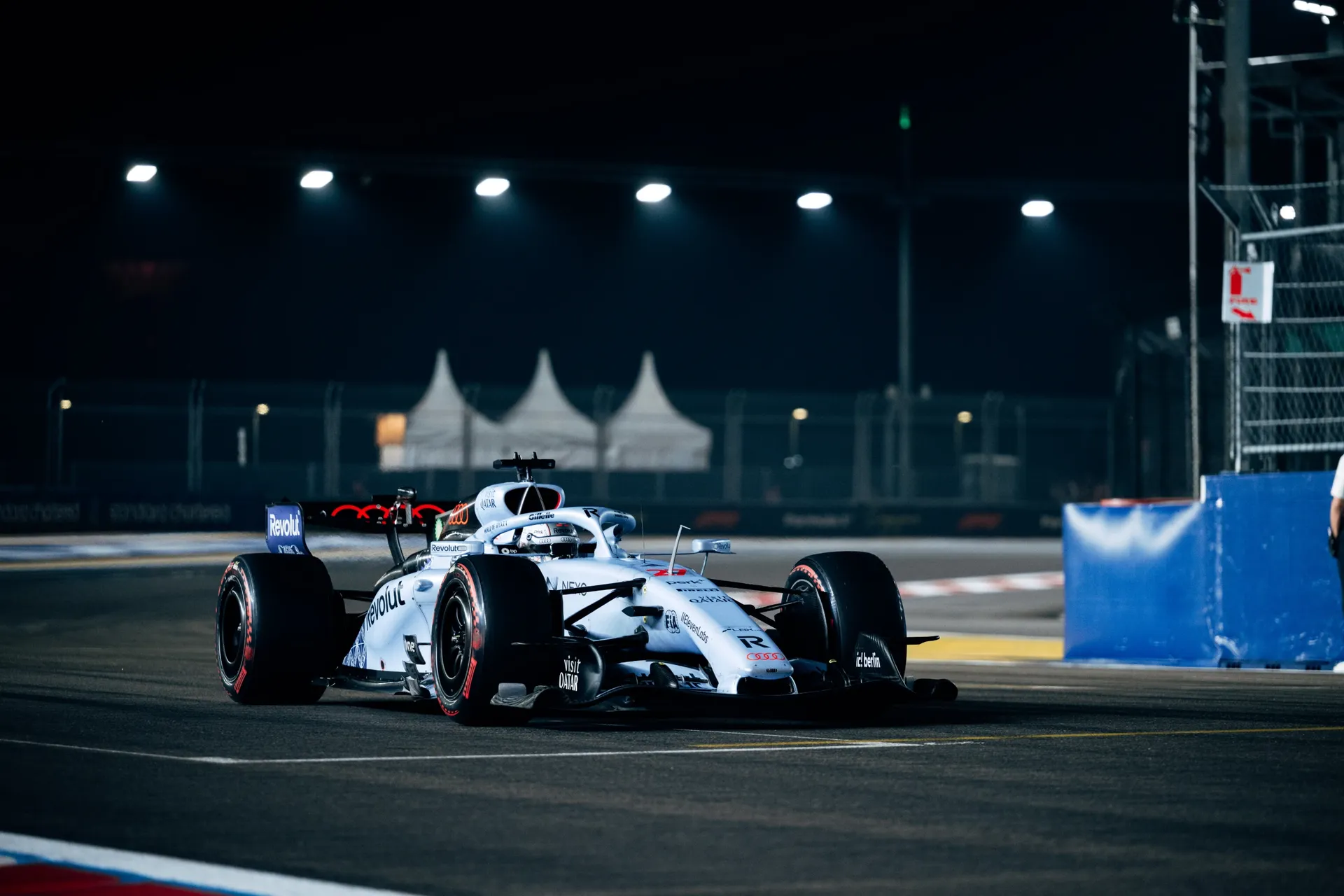 Car in Singapore special livery of the Audi Revolut F1® Team with a driver in a white helmet on track at night in Singapore