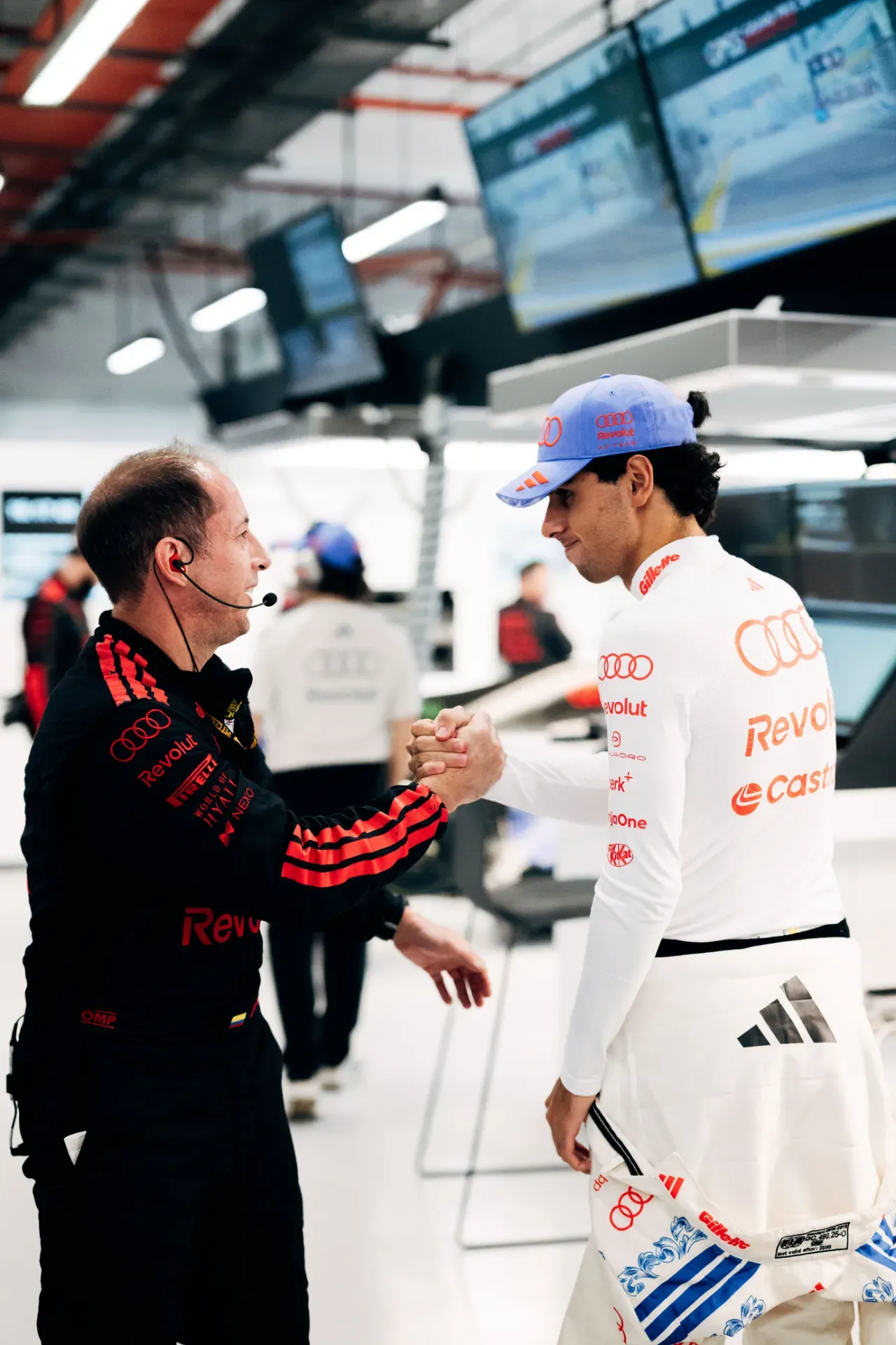 Gabriel Bortoleto of the Audi Revolut F1® Team shakes hands with an engineer in black overalls in the garage in Singapore